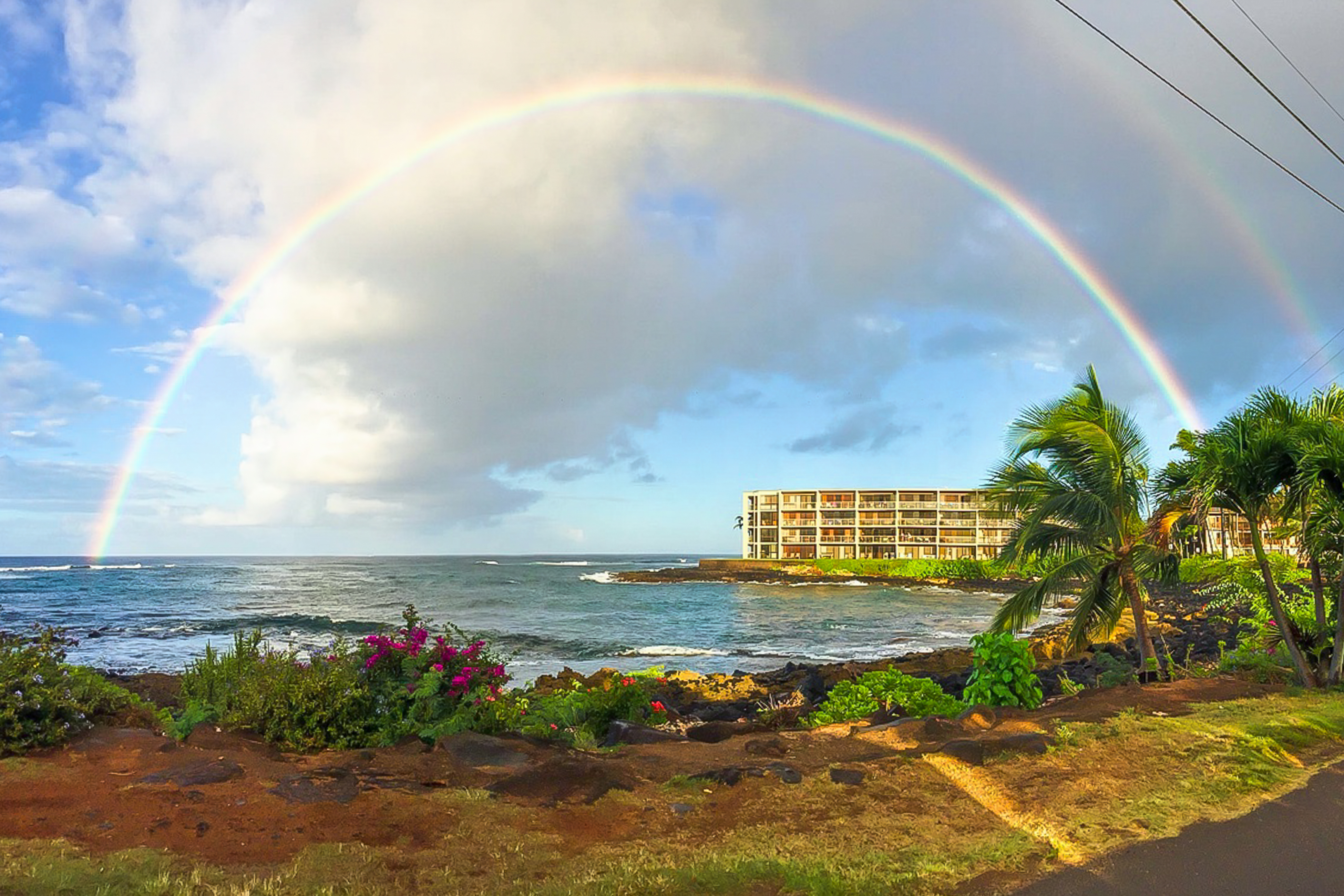 A double rainbow over an ocean shore near a resort in Kauai, HI.