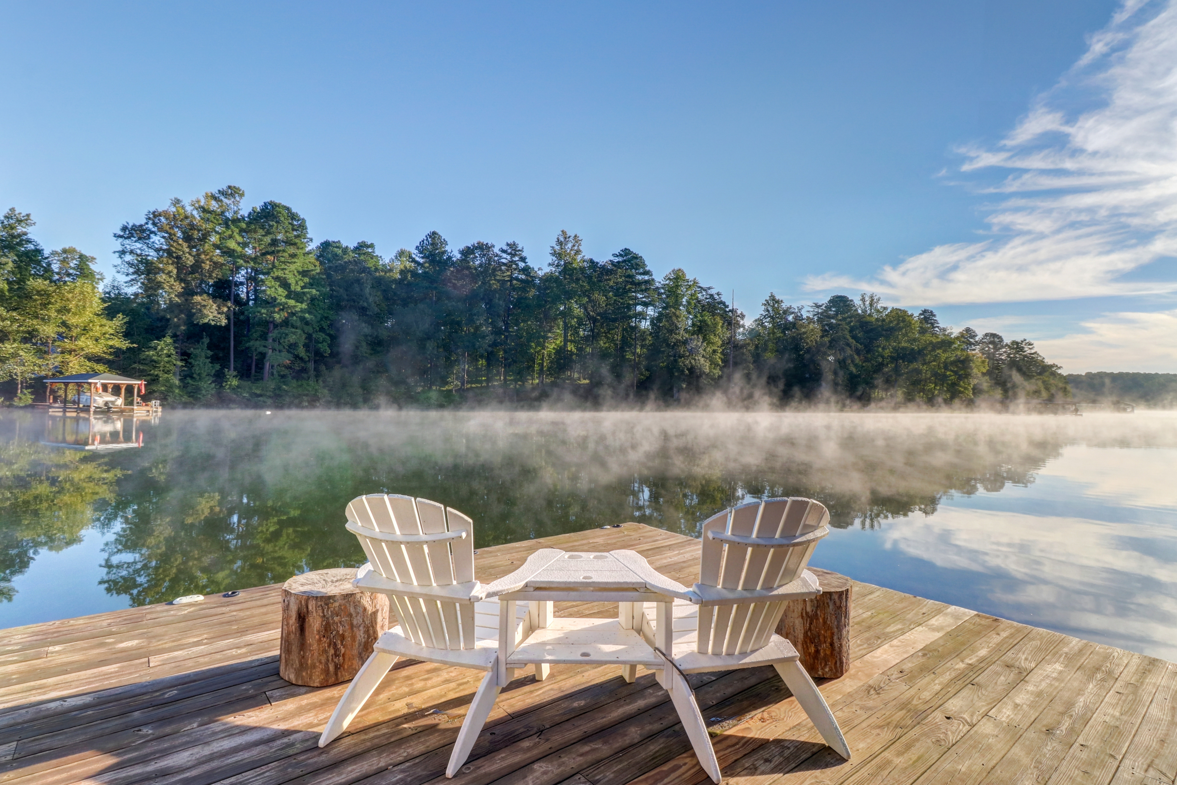 Two white adirondack chairs look out over Lake Anna in Virginia on a sunny day