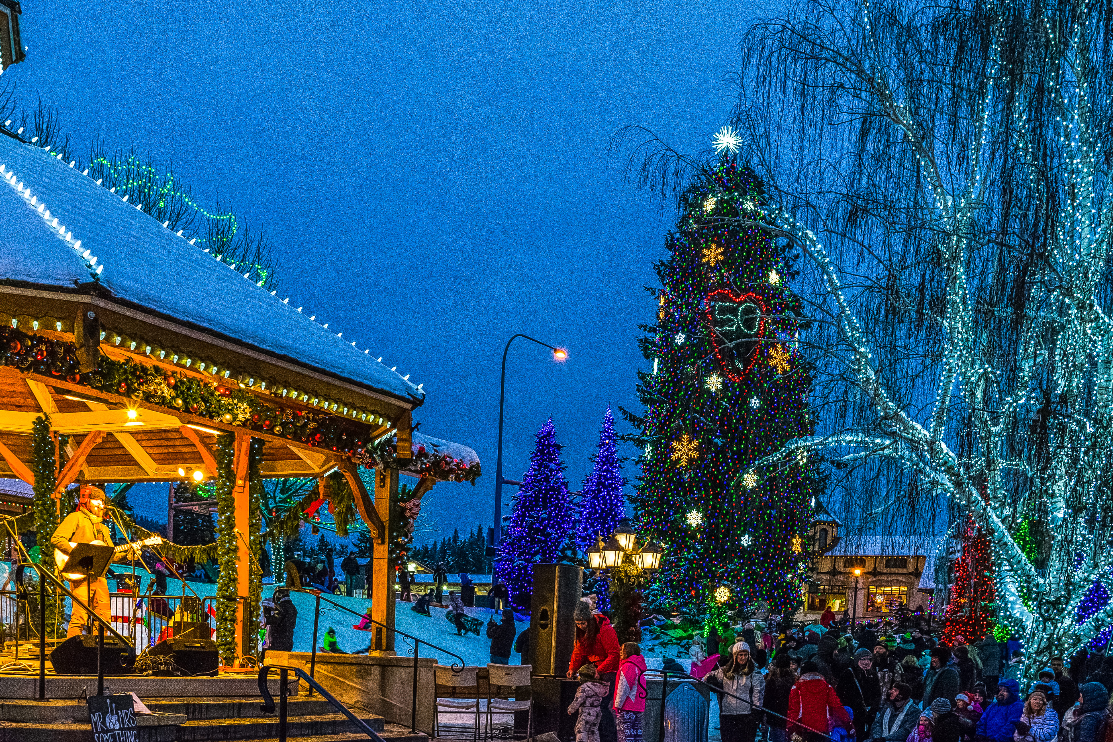 Band performing at a public outdoor gazebo to a crowd with Christmas decorations in Leavenworth, WA