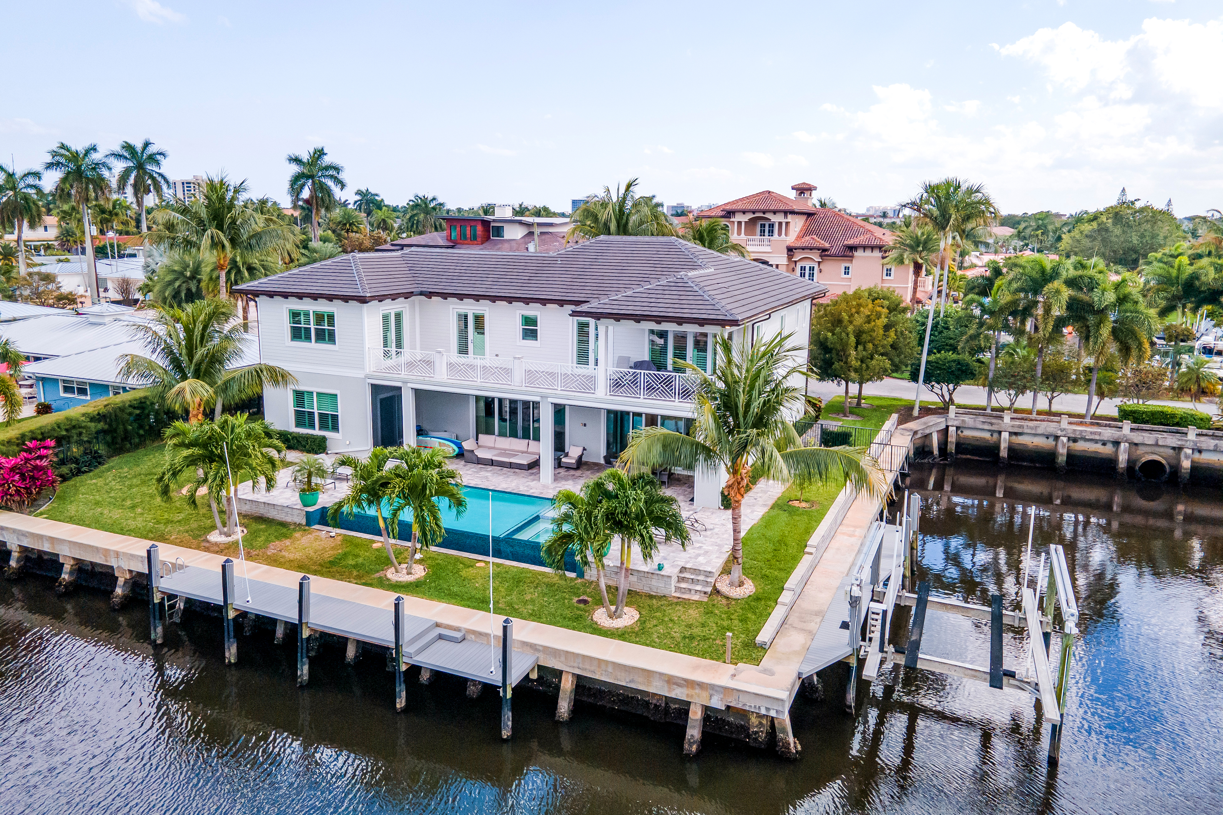 The back exterior of a Martin County vacation rental with a pool, dock, and other high end amenities.