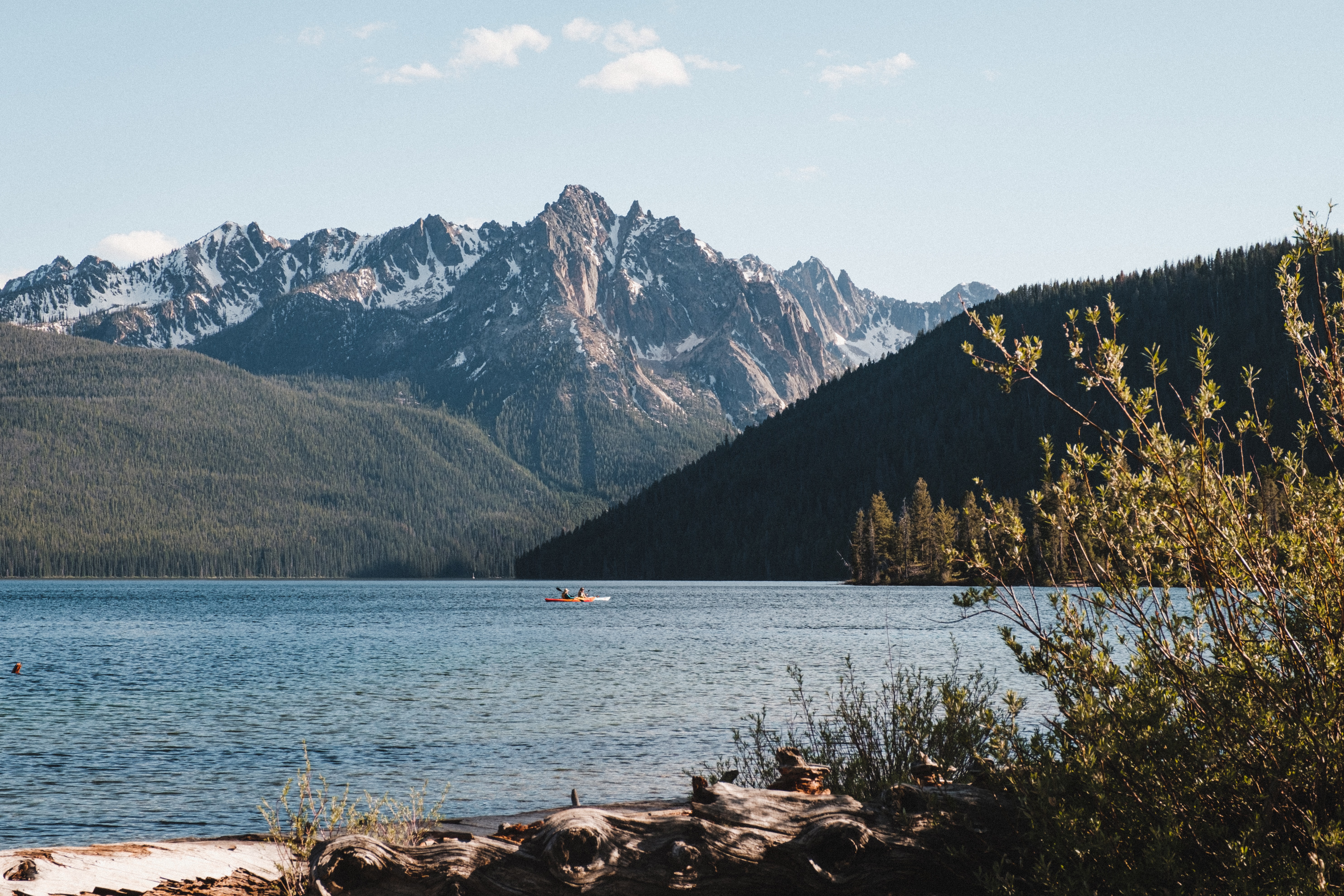 A kayaker in a large lake in the mountains during the day.