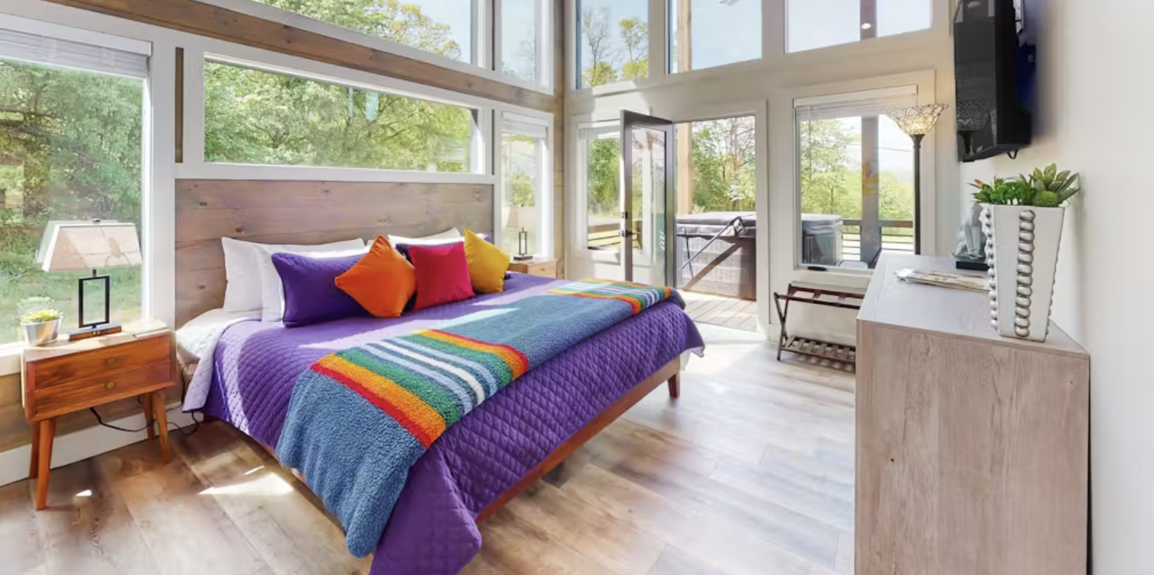 A bed with colorful design at a vacation rental with large windows in Blue Ridge, Ga.
