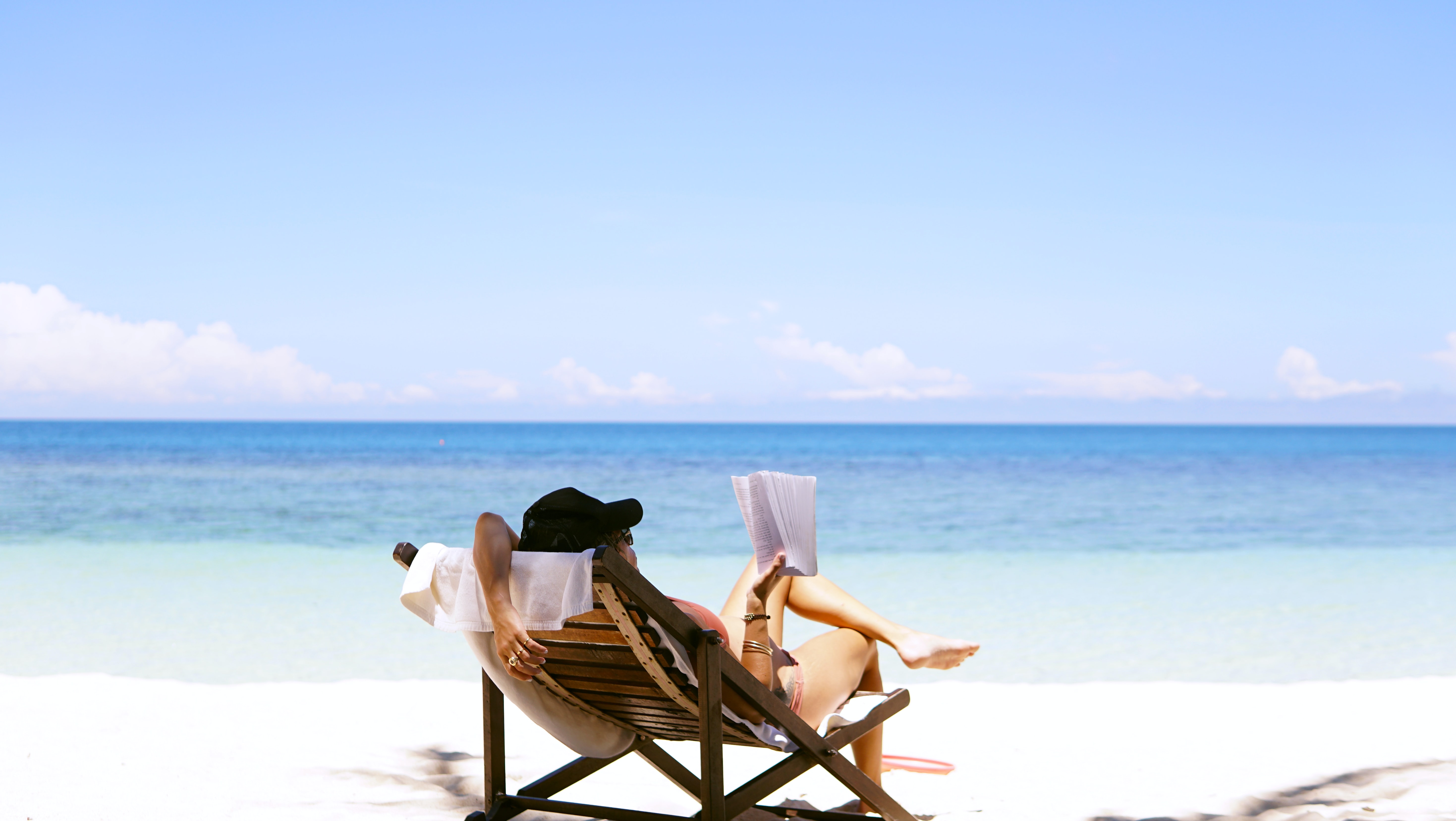 woman relaxes in a beach chair while reading a book
