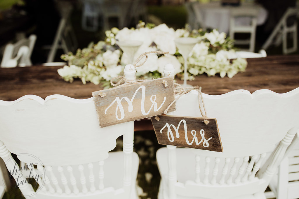 Sweetheart table with two white chairs and decoration saying "Mr" and "Mrs"