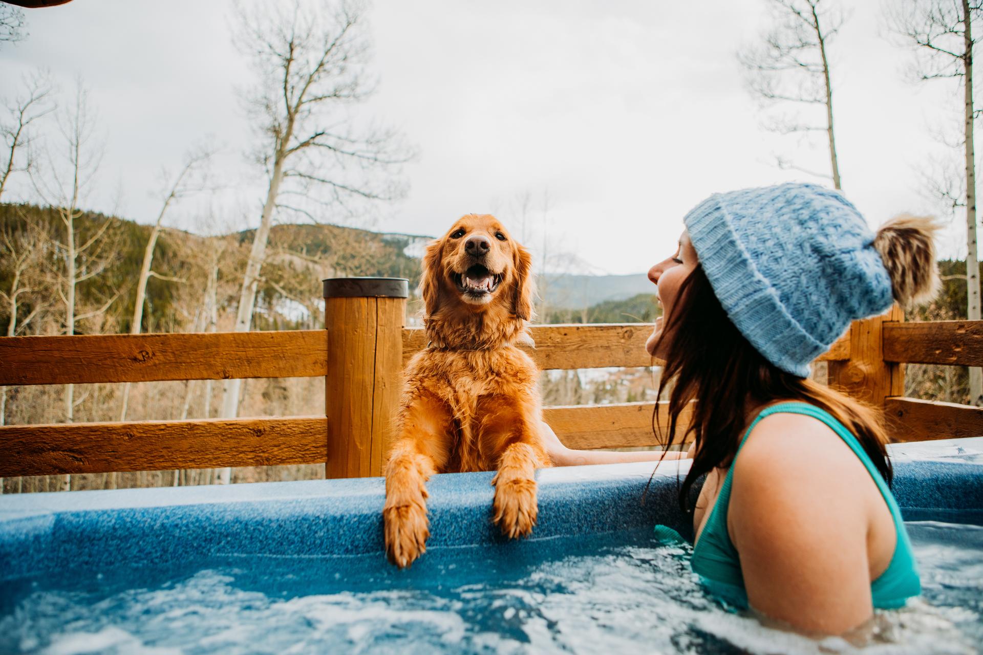 Girl in a hot tub with a dog on the side.