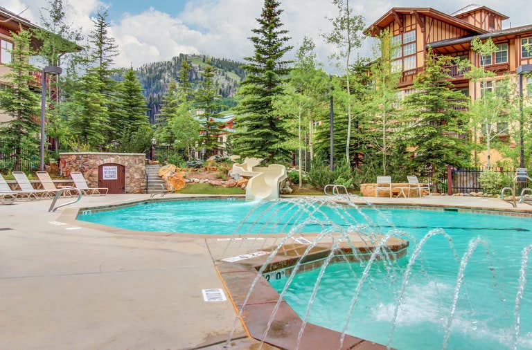 pine trees surround outdoor pool with water slide at Powderhorn Lodge