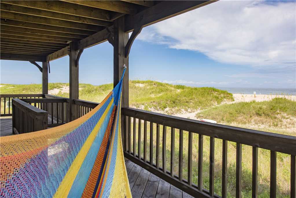 A hammock hanging from a wooden outdoor patio facing a sandy beach in Rodanthe, NC.