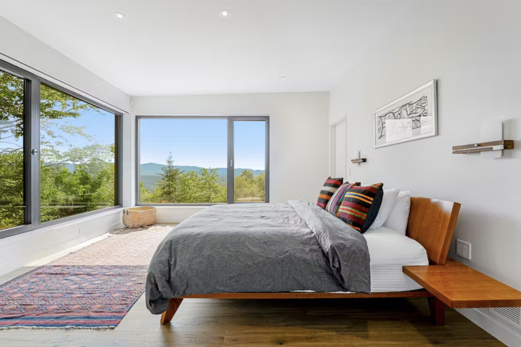A bedroom with elegant design and large windows overlooking the mountains at a vacation rental in Vermont.