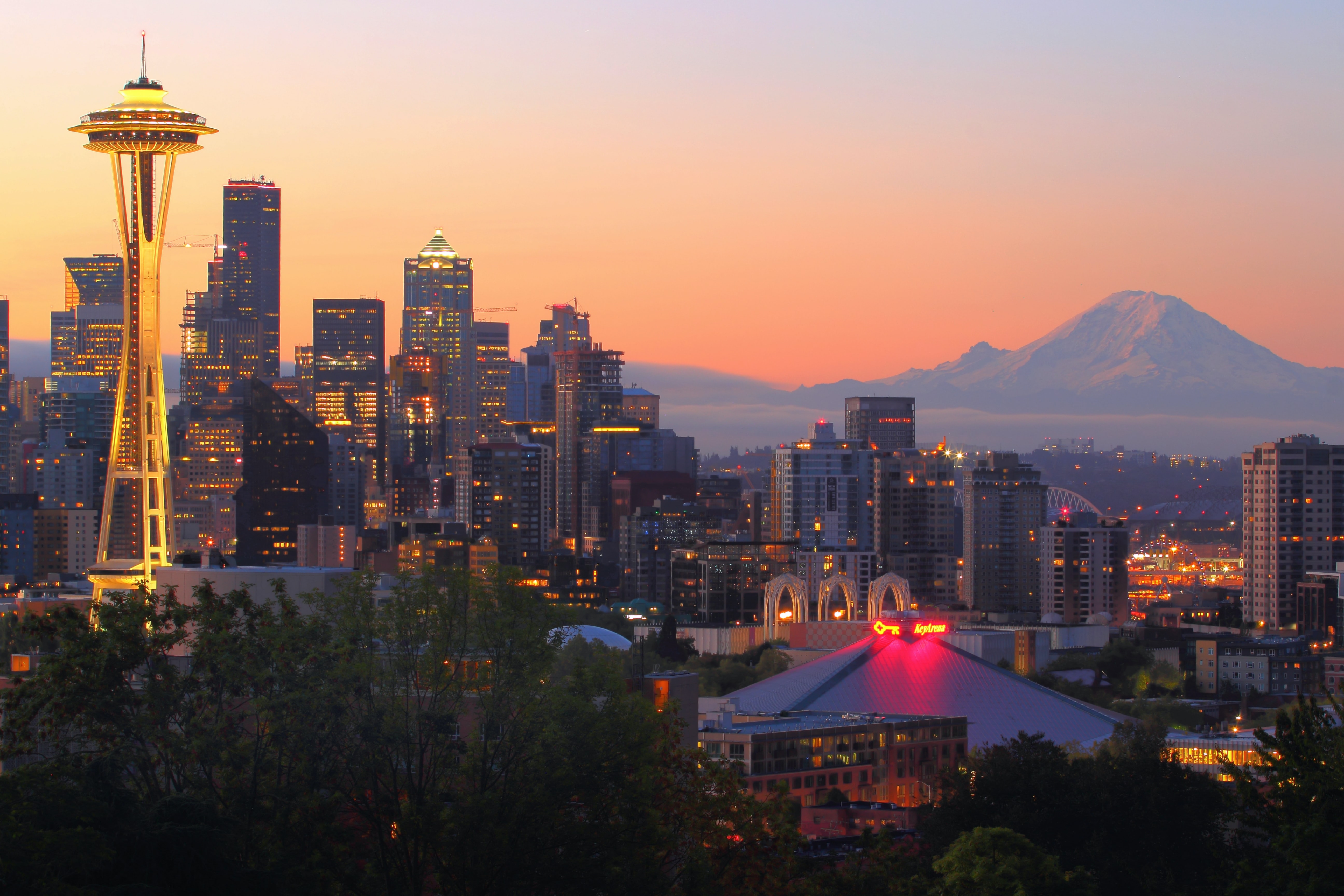 A view of Seattle, WA with the Space Needle and sky scrapers and a large mountain in the distance.