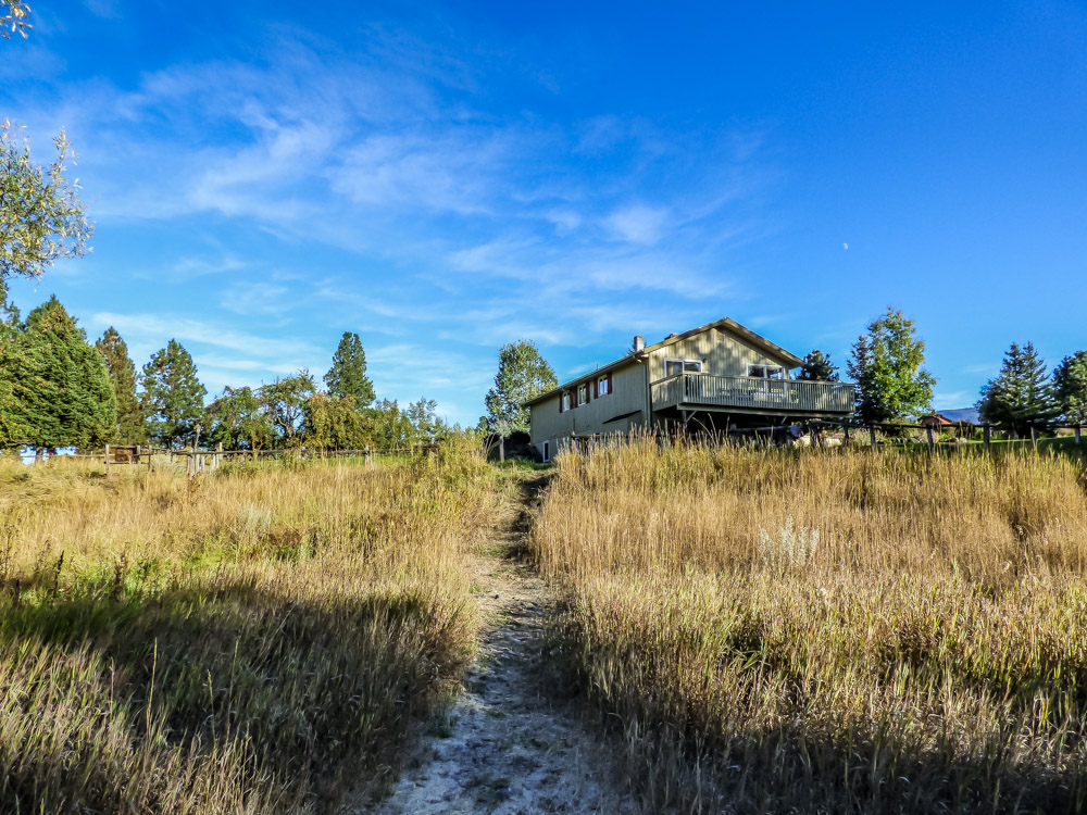 Grassy field with a path towards a large house at Wallowa River Camp