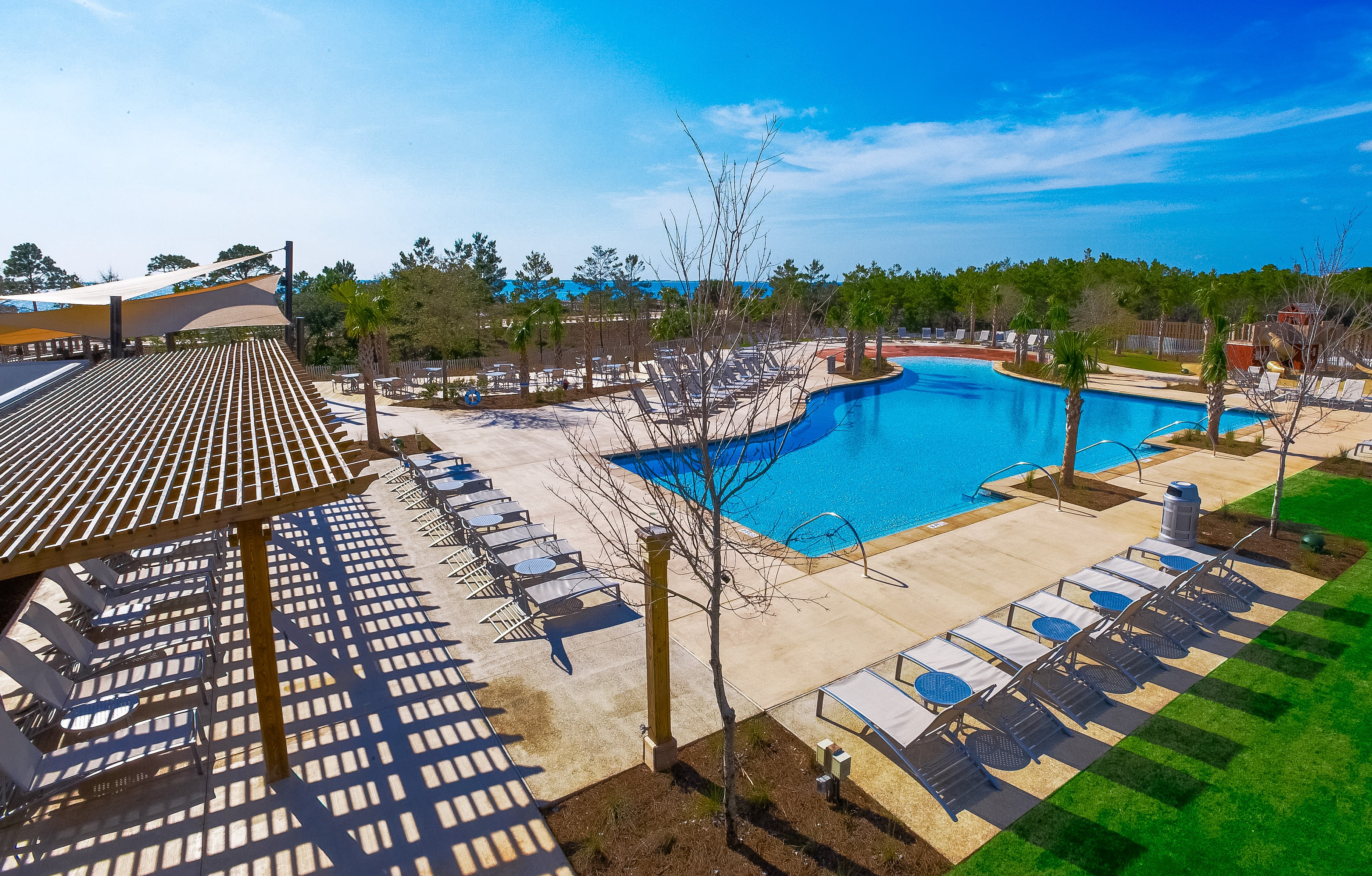 Large resort pool with lounging pool chairs set out on a sunny day