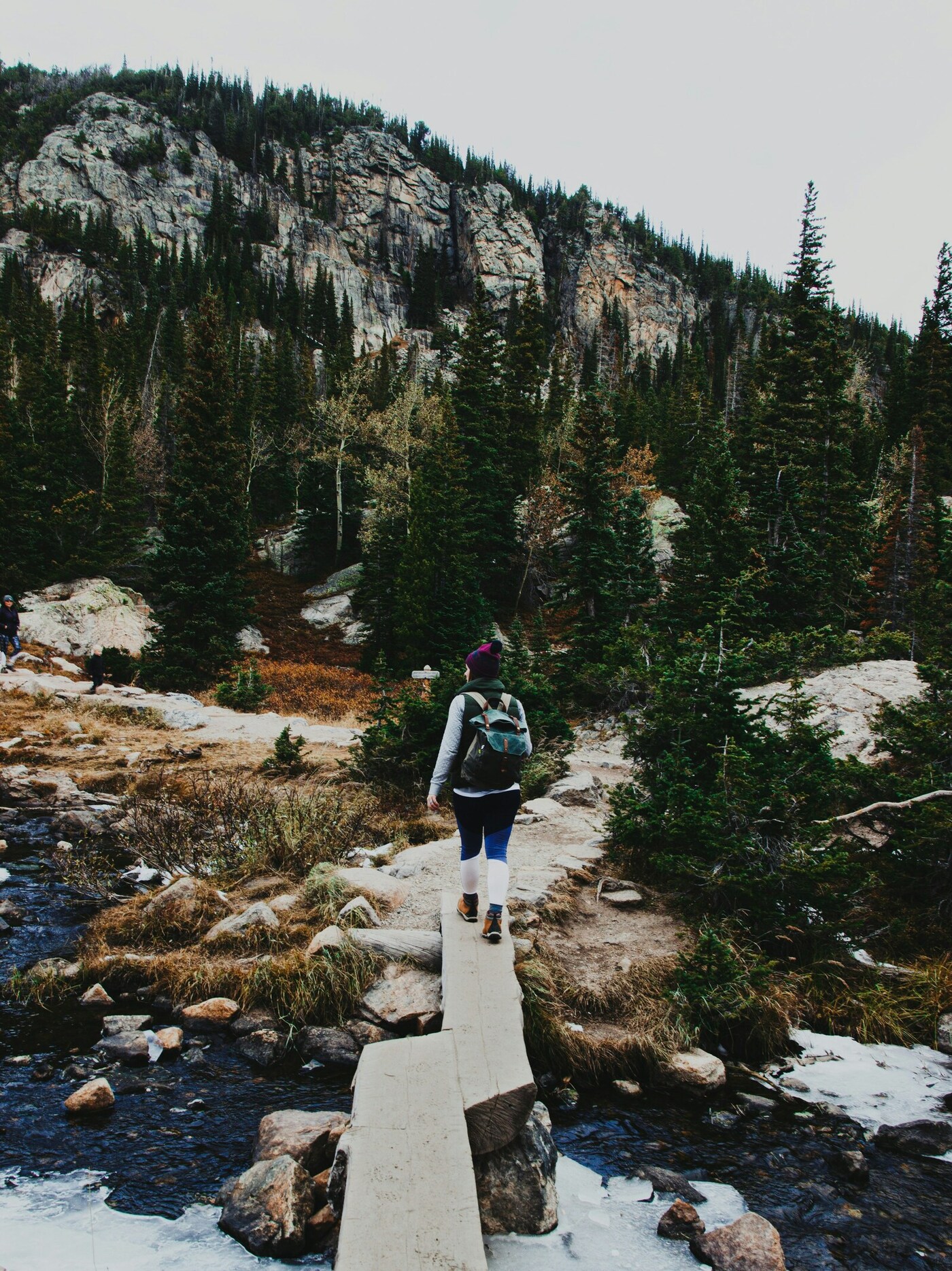 person walking across a bridge on a trail in the Rocky Mountains