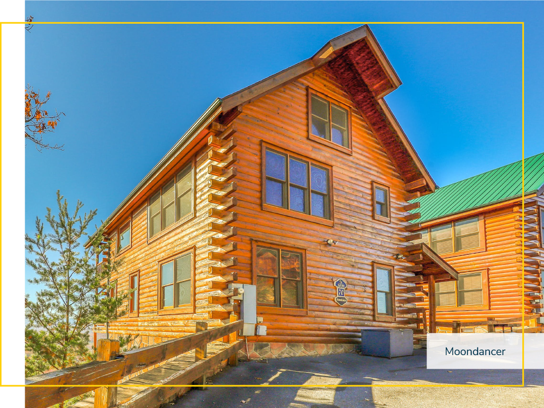 Two story cabin with a wooden fence along a cliff on a sunny day.