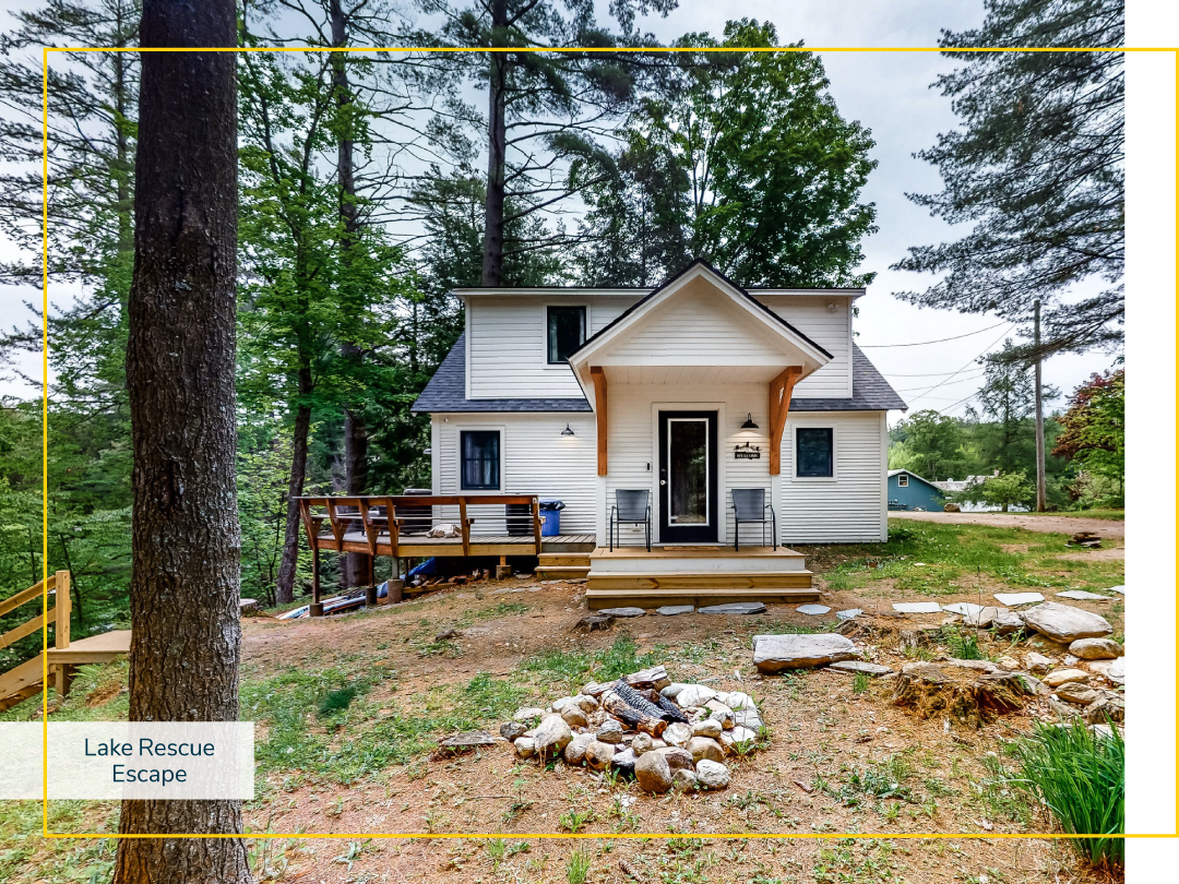 A vacation home with a wooden deck and patio in the woods on a slope during the day.