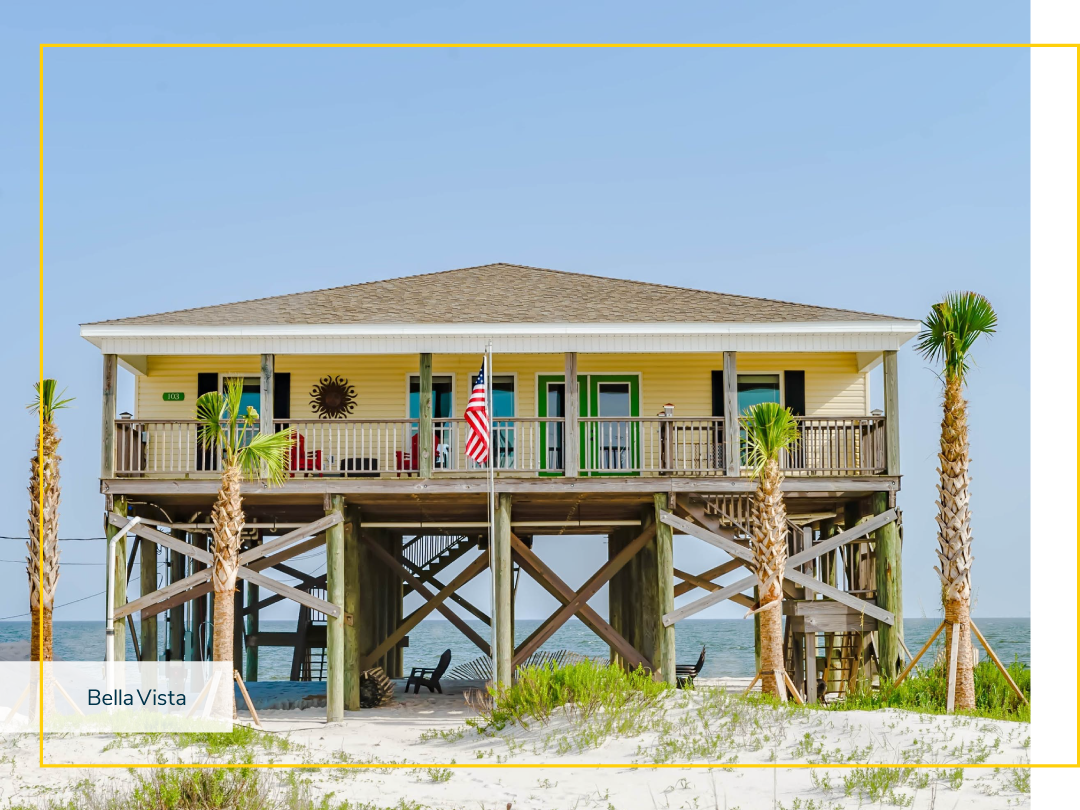 A vacation home built on tall wooden beams on the shore of a sandy beach.