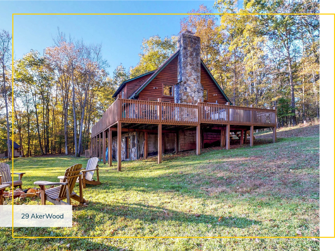 Wood cabin on an uphill slope with an outdoor fire pit and adirondack chairs.