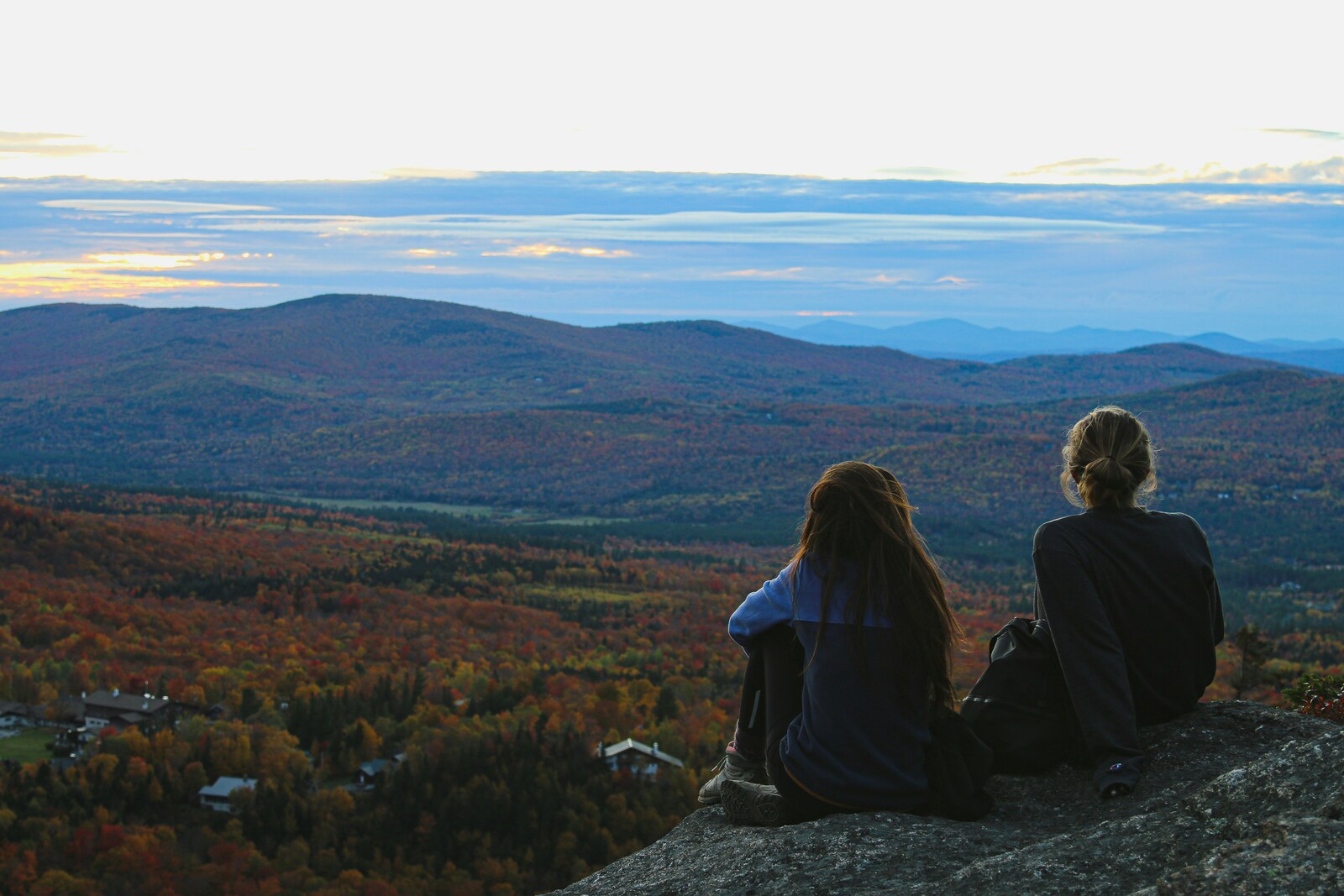 two people resting at a mountaintop viewpoint overlooking the White Mountains