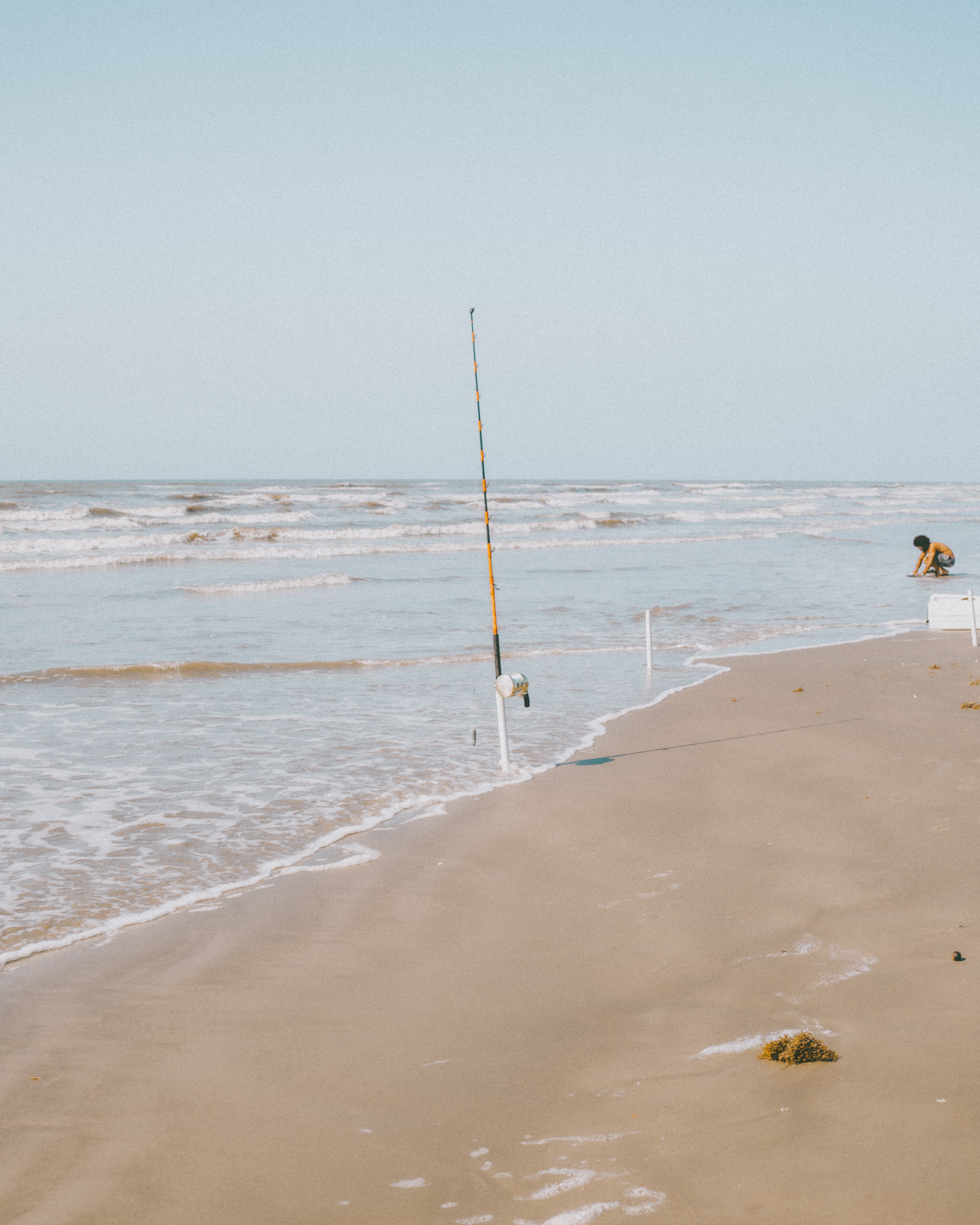 Image of a fishing road fishing in the ocean with a guy to the left.