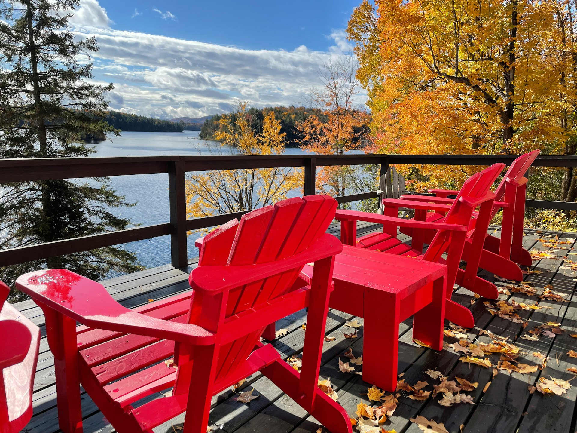 unsplash photo of red chairs sitting on balcony overlooking a body of water in the fall