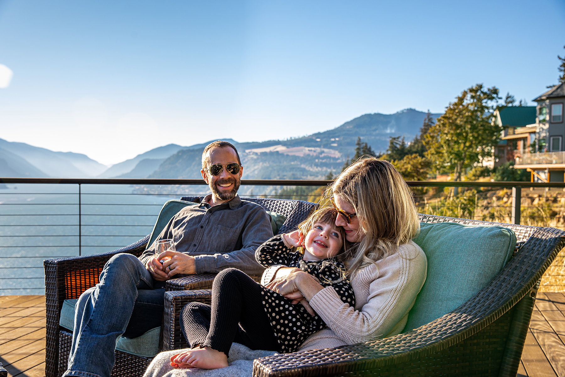 A couple on a deck overlooking a river holding a baby.