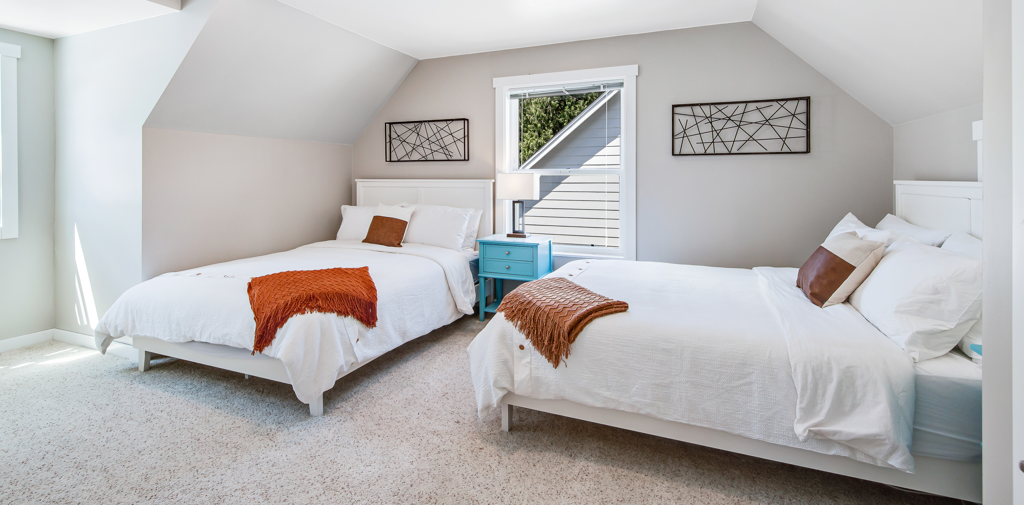 two beds with white bedding and orange throw blankets