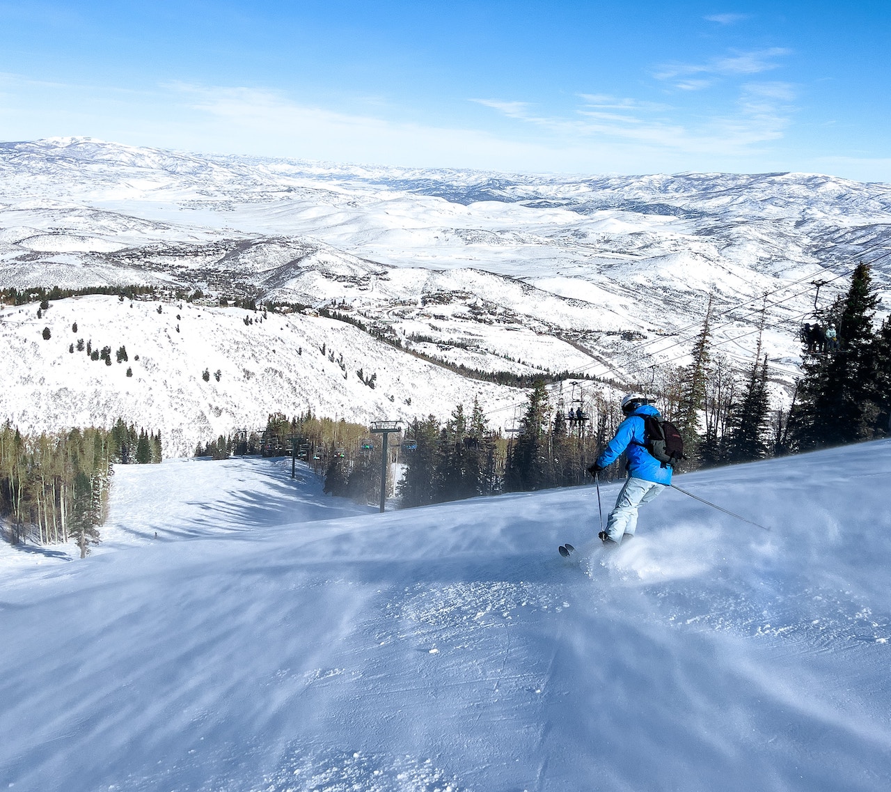 A skier glides down the mountain as a gust of wind makes the surface crawl.