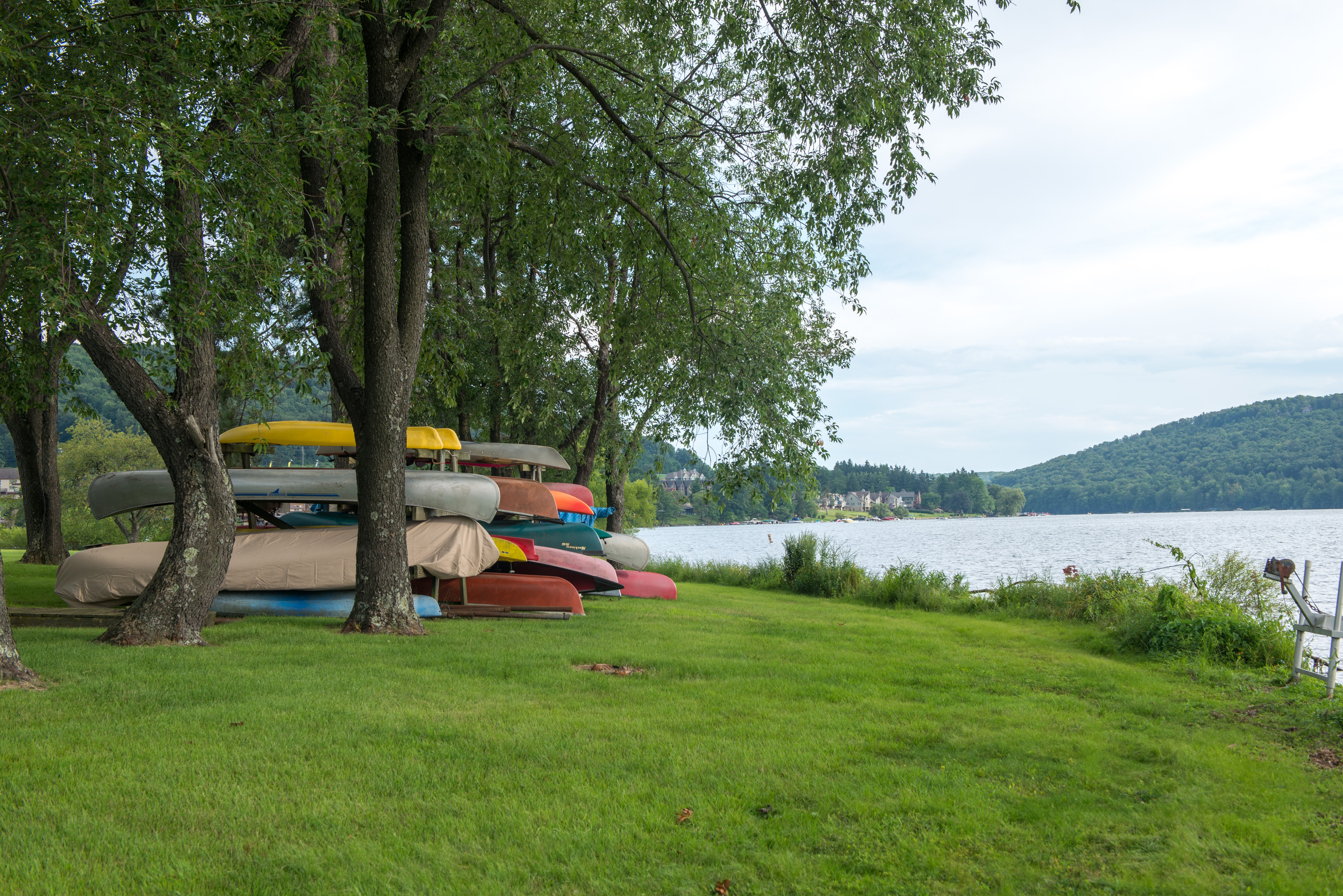 Canoes stacked on racks on a grassy field near the shore of Deep Creek Lake