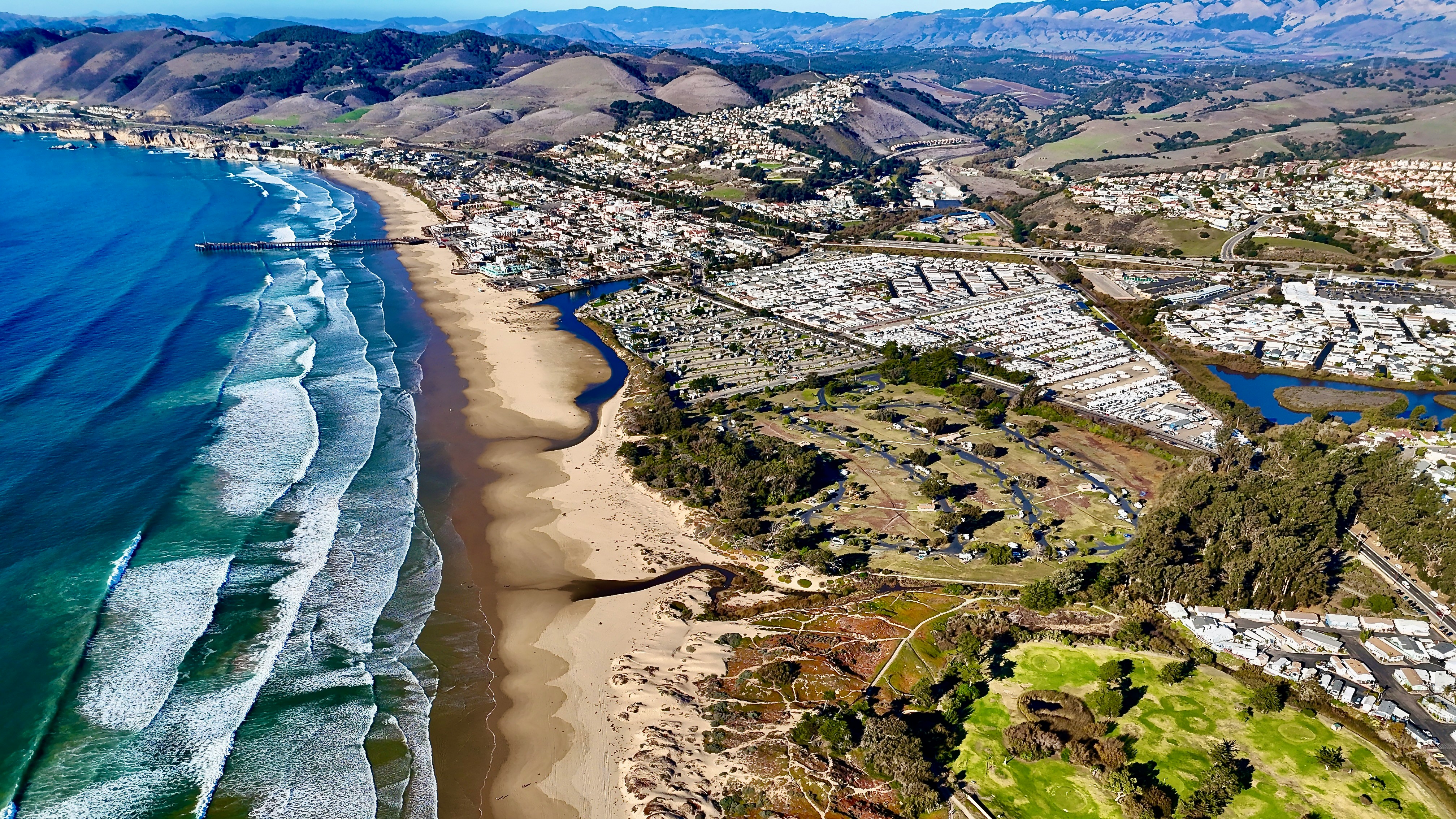 aerial view of pismo beach with the hills and mountains beyond the city
