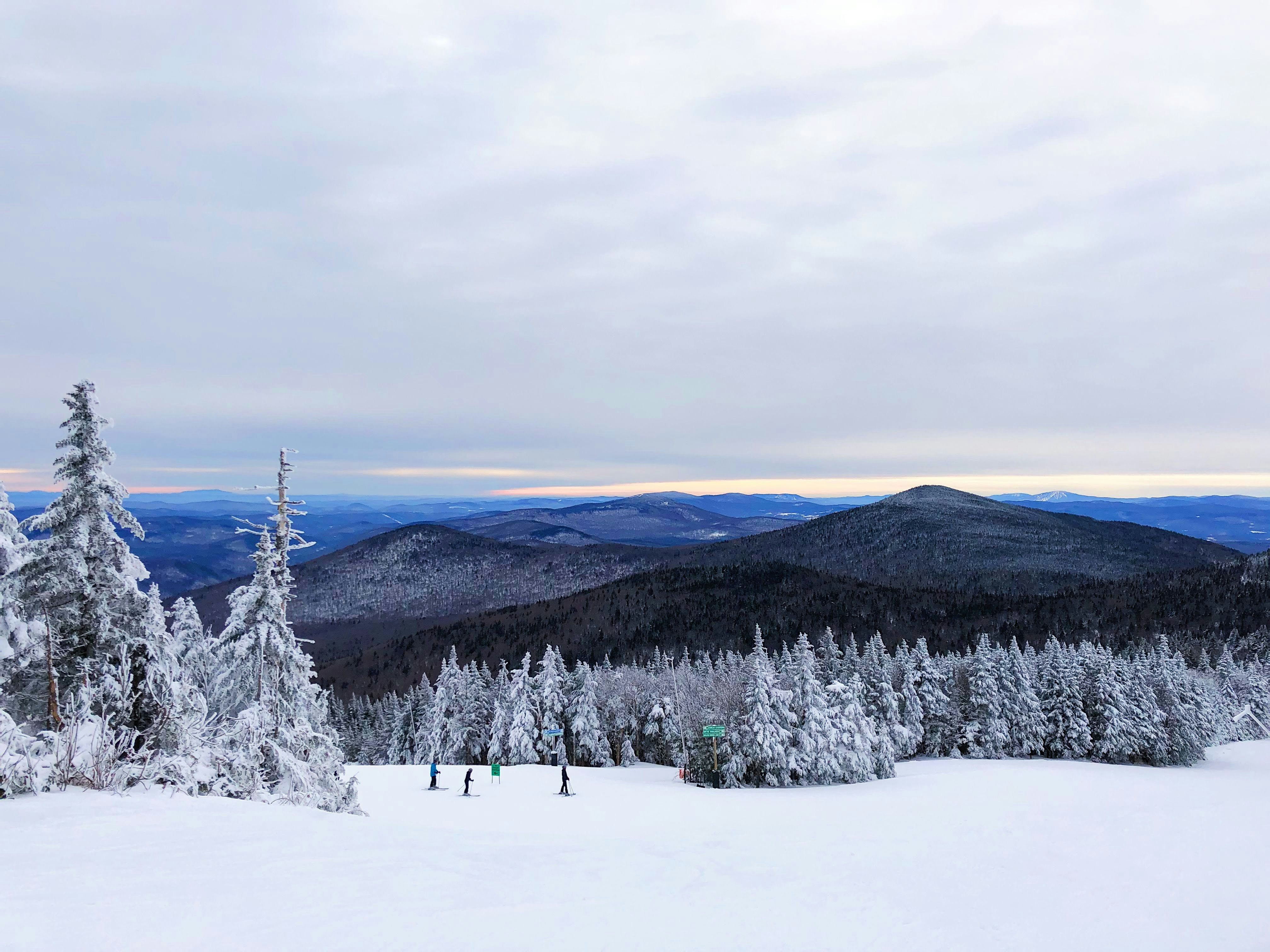 a few skiers traverse the snowy mountains in killington, vermont