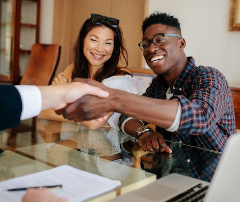 woman smiles as two people shake hands