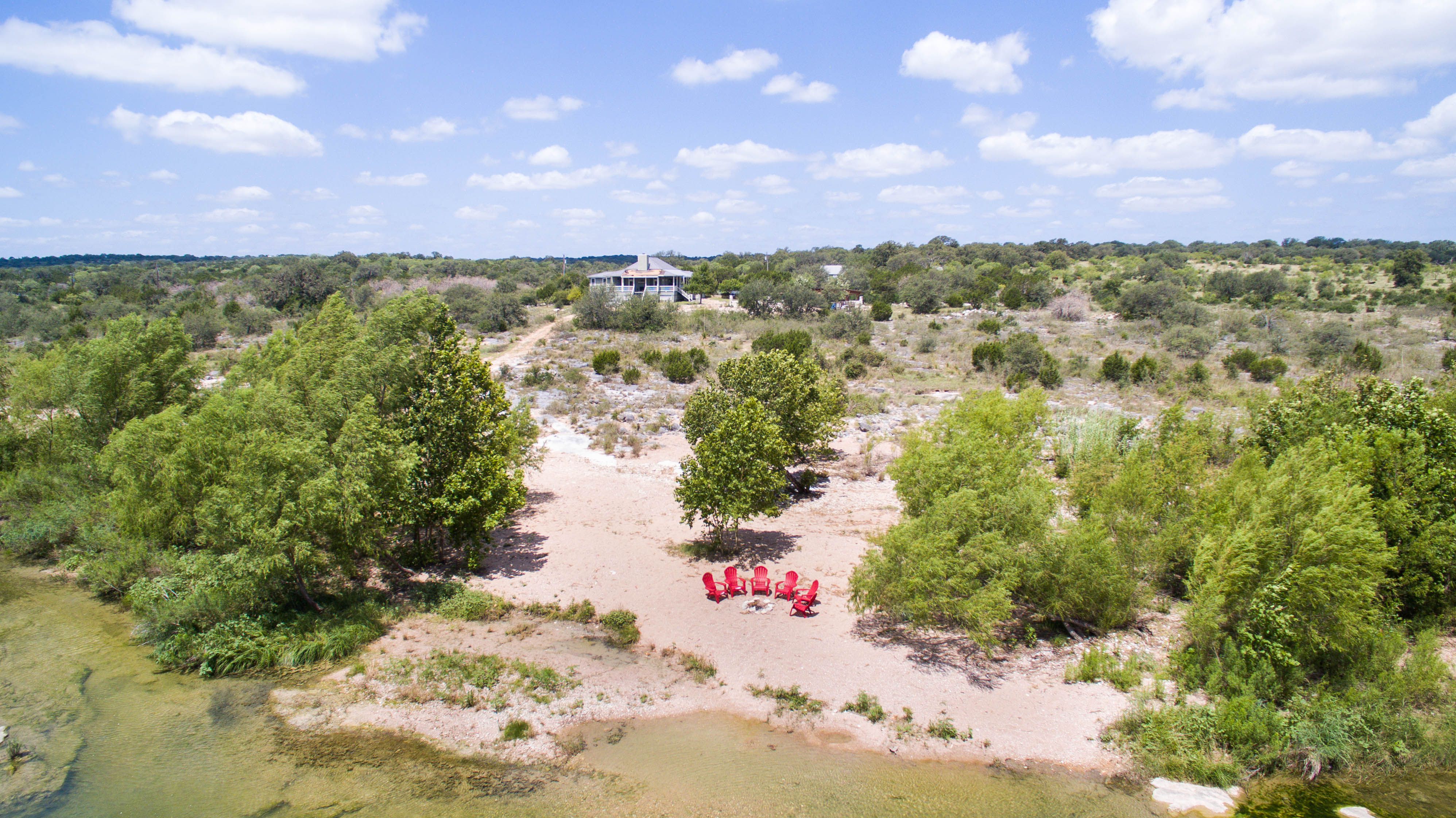 chairs arranged in front of a firepit next to a river in texas