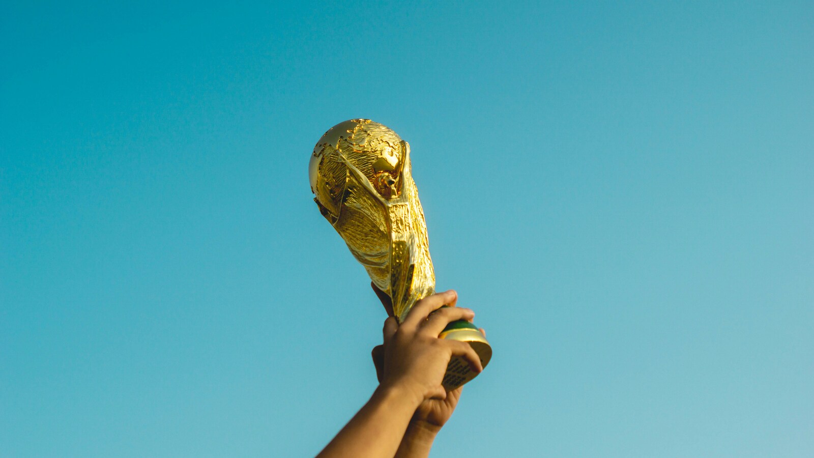 person holding up FIFA trophy