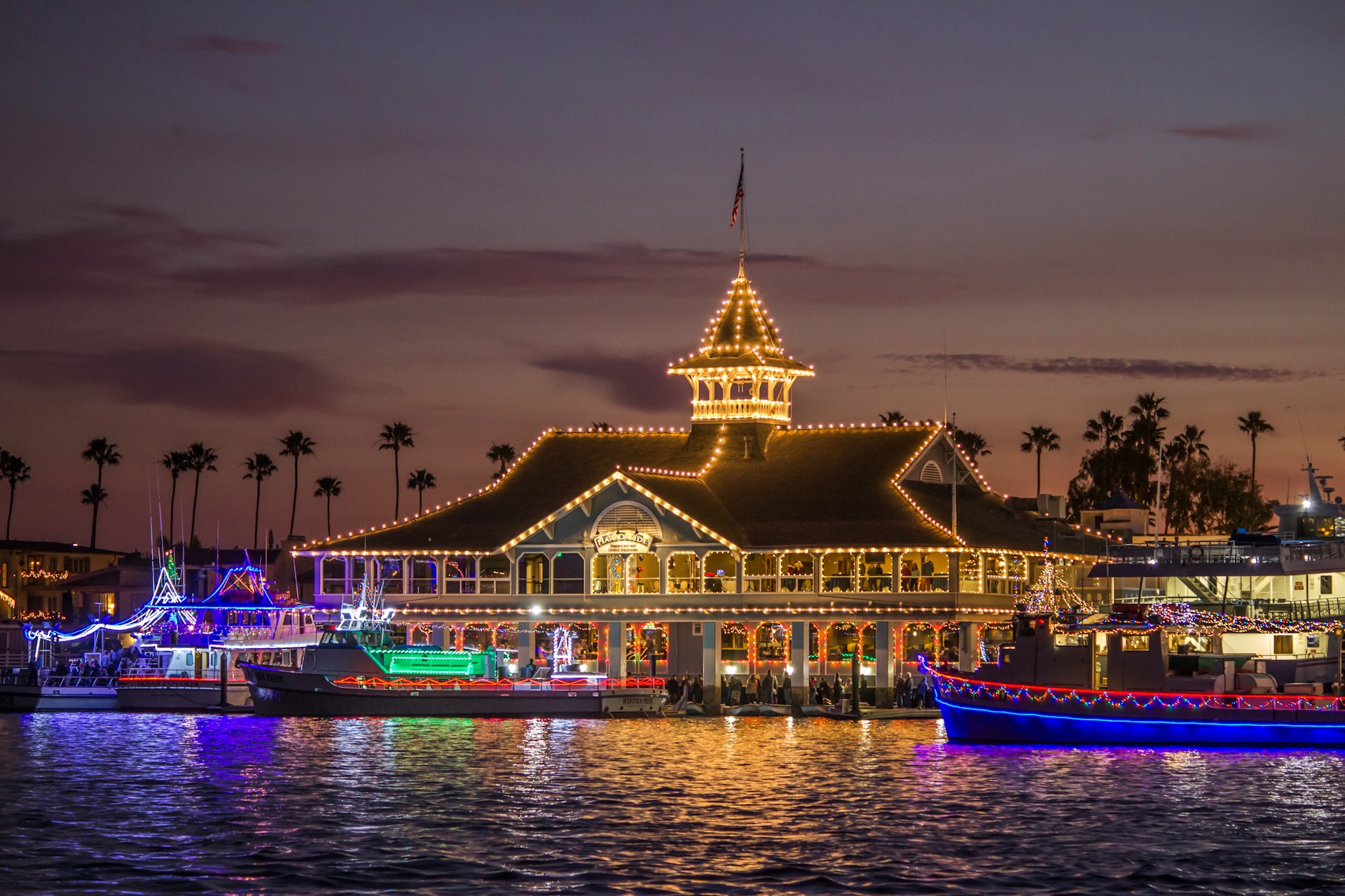 Boats and a building decorated in Christmas lights at a marina in San Diego, CA.