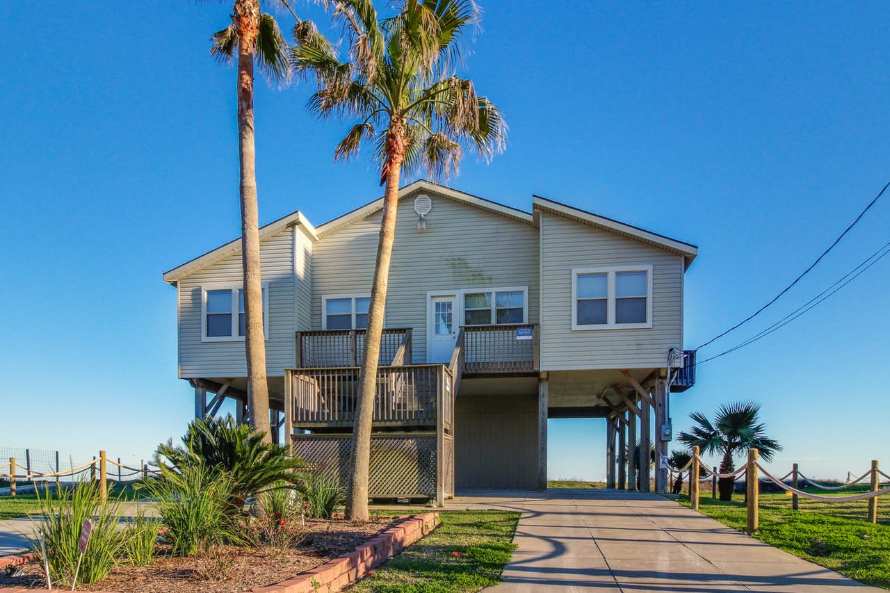Galveston, TX vacation home with palm trees and blue skies