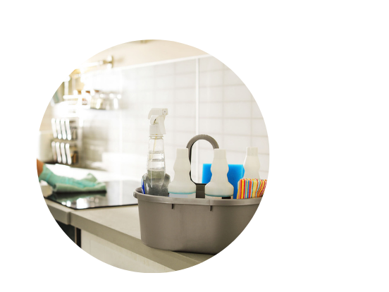 cleaning supplies caddy with someone cleaning a stove in the background