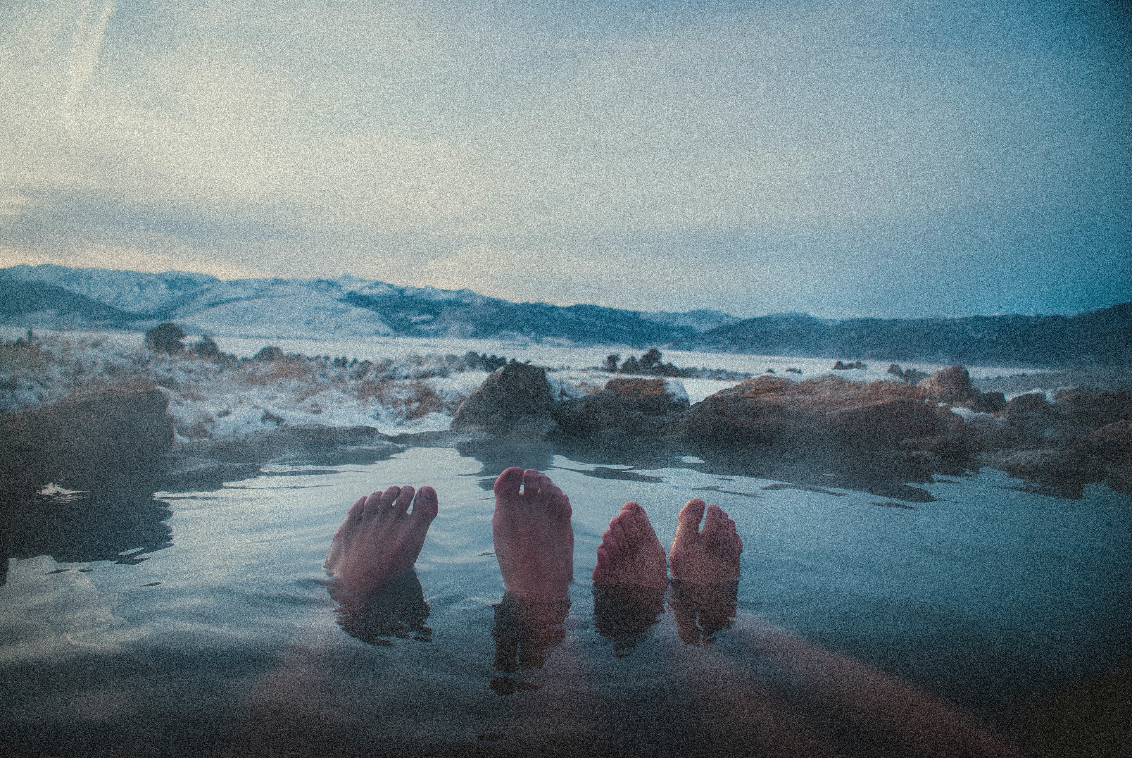 Two people with their feet out of the water in a hot spring.