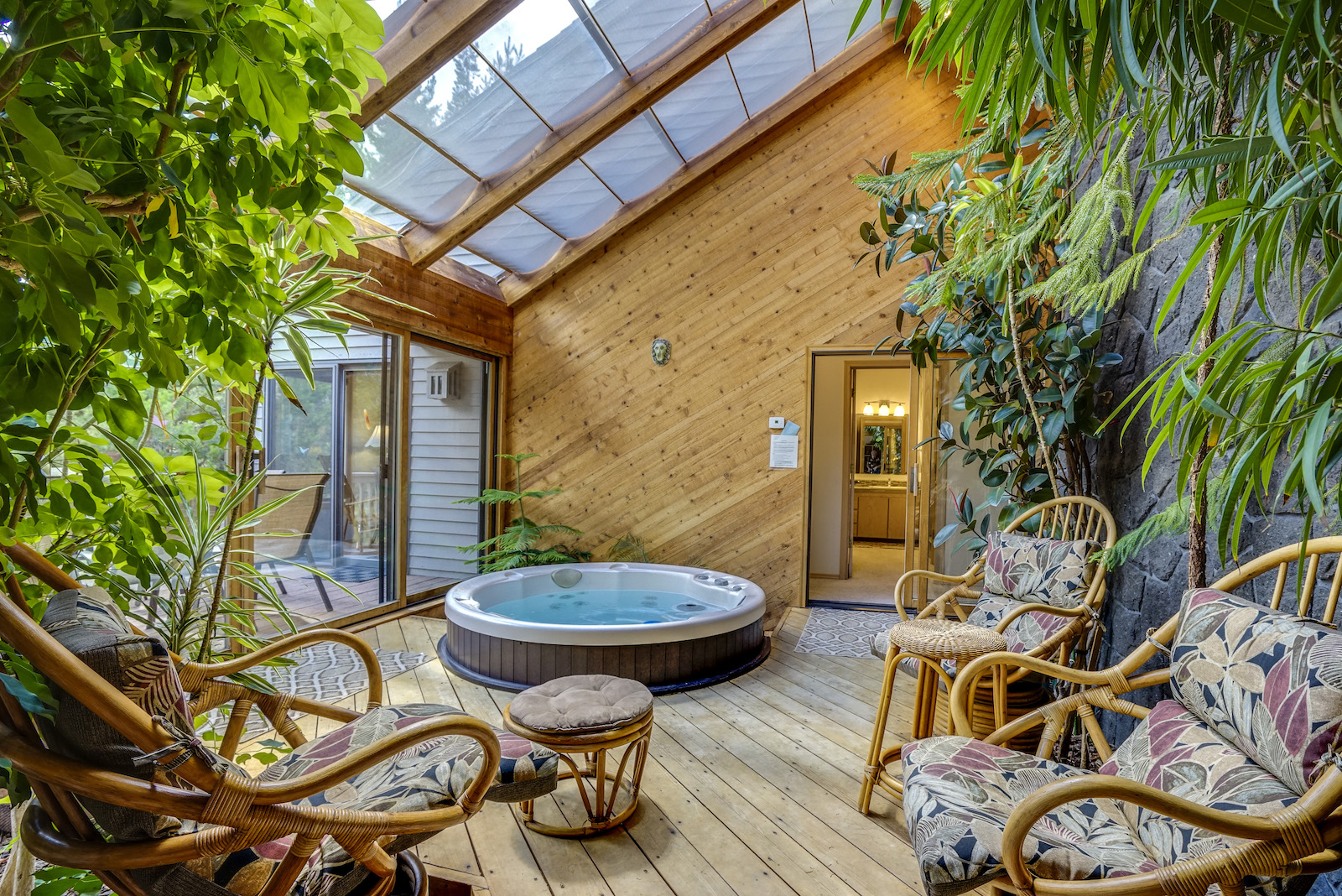 A sun room with a hot tub and covered deck at a vacation rental in Sunriver, Oregon.