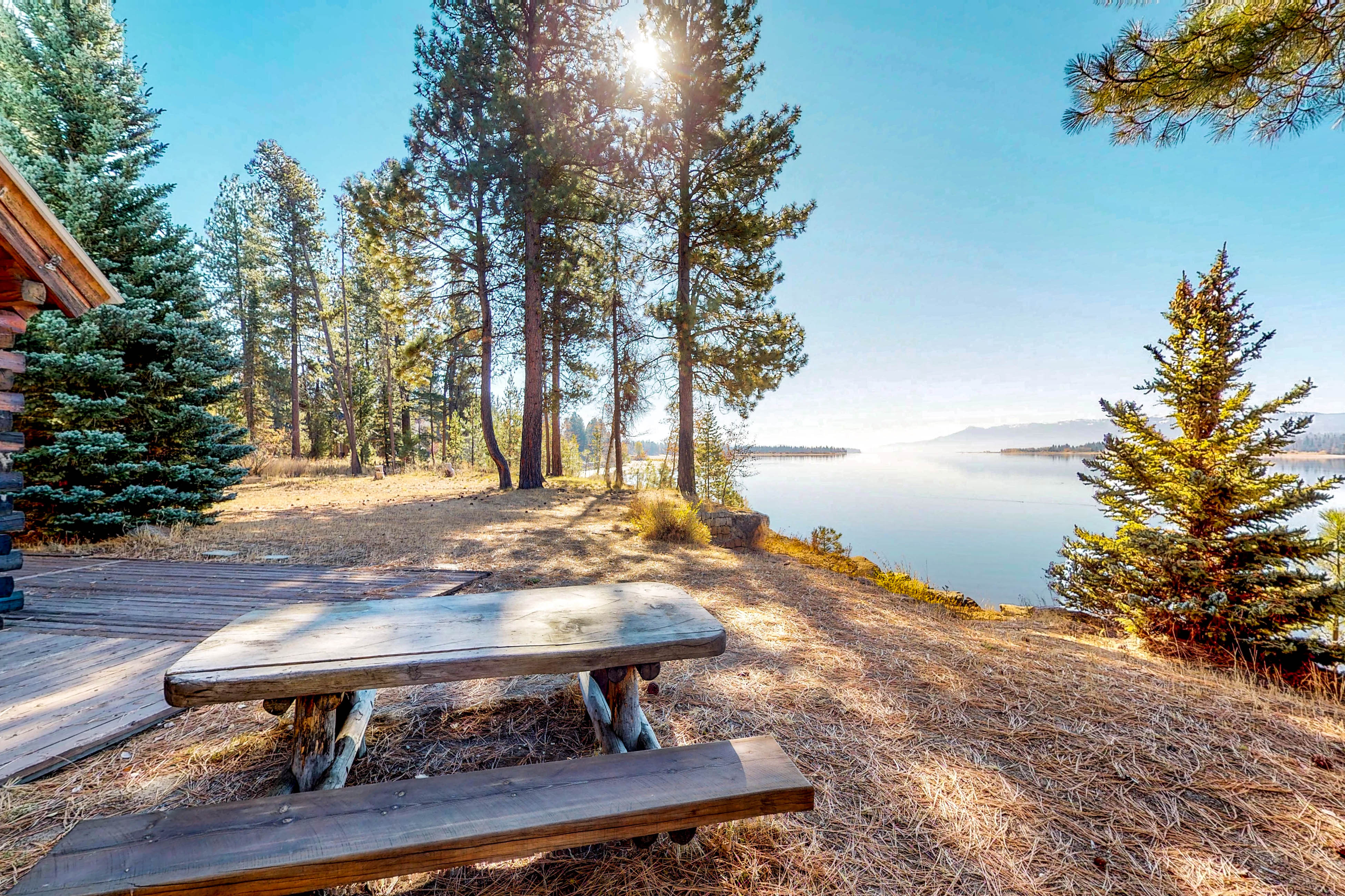 Outdoor wooden table bench facing a large lake during the day in Idaho.