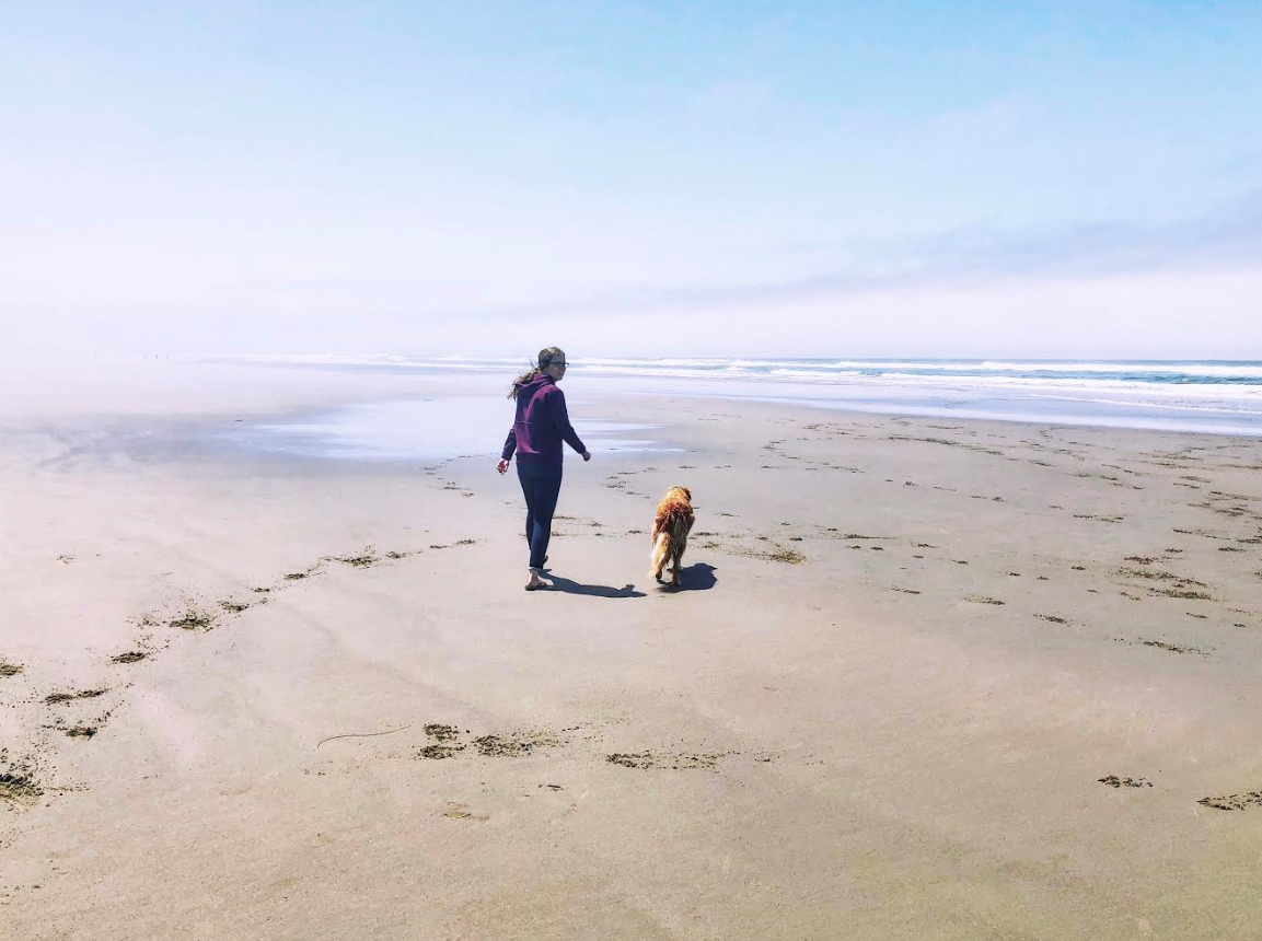 Rusty and his owner walking along the beach in Pacific City, OR