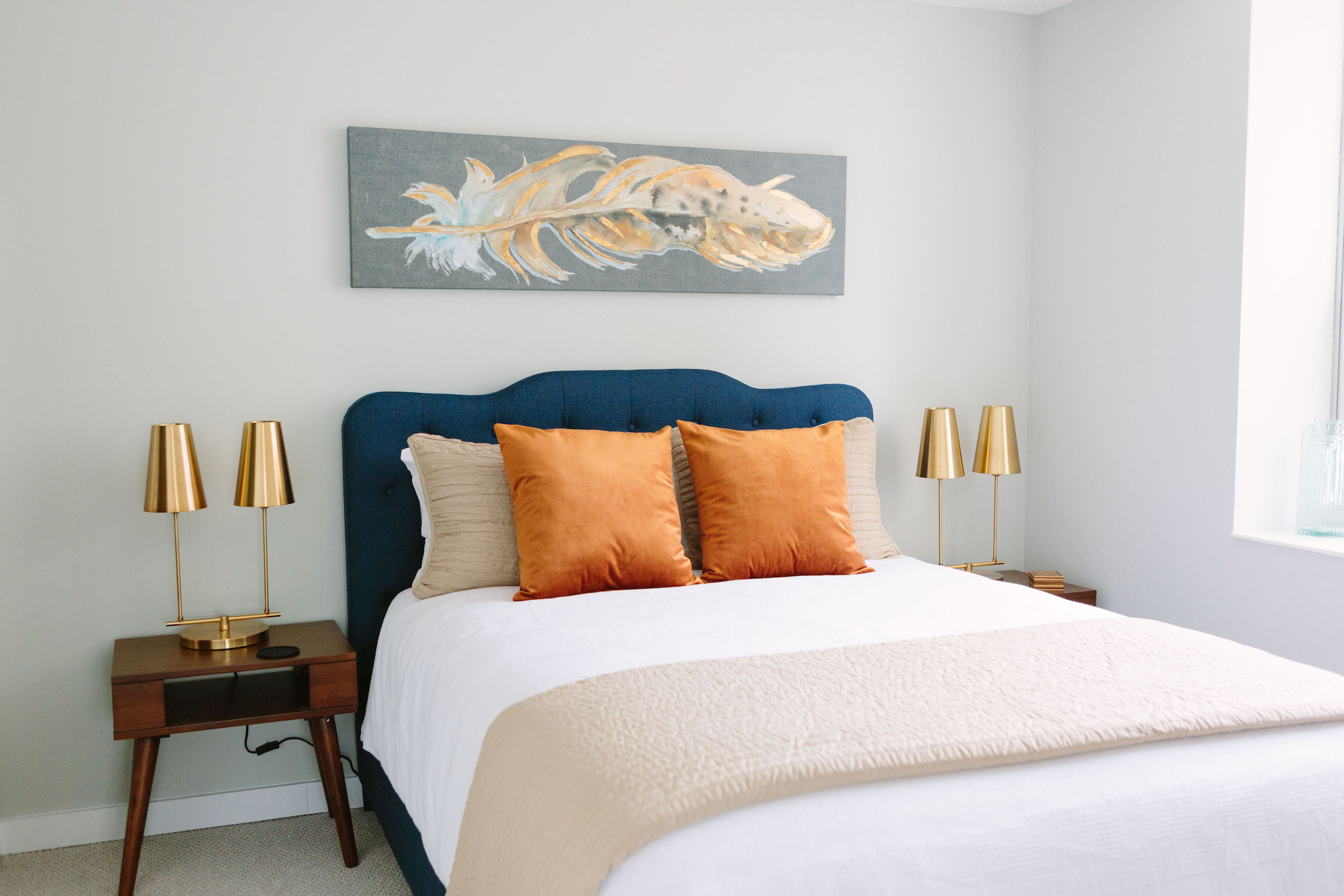 Inside a bright bedroom with a professionally well-made bed with modern style night stands.