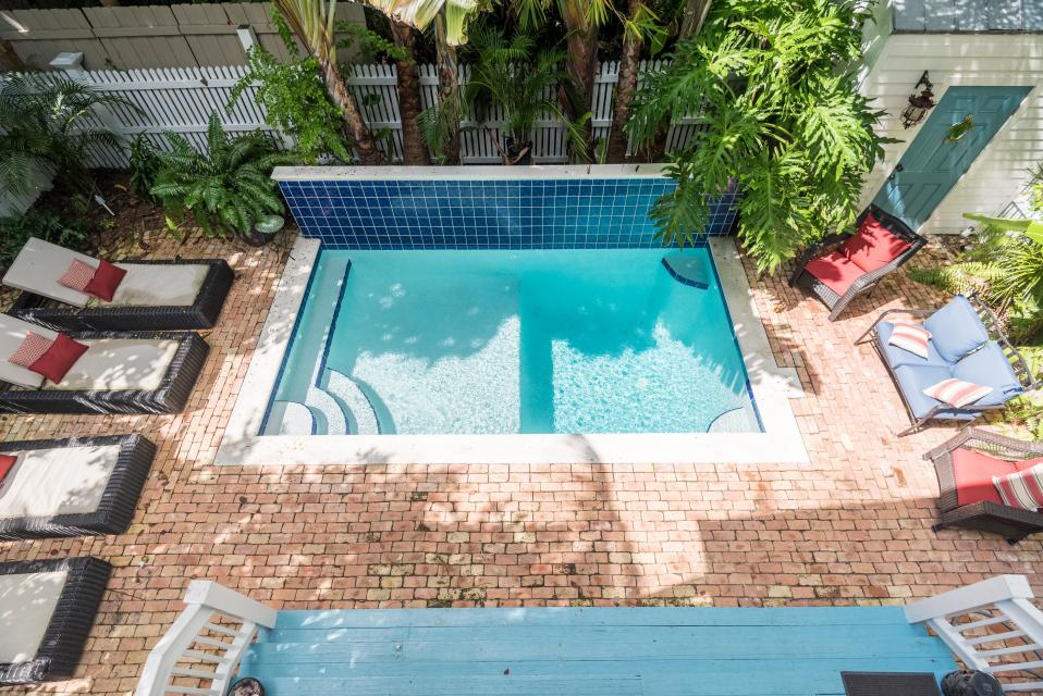 Backyard of a Key West, FL cottage with outdoor pool and pool chairs.