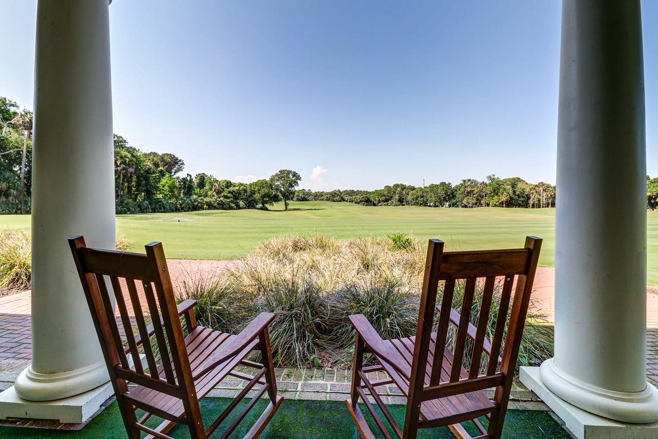 two rocking chairs overlooking a golf course on a cloudless day