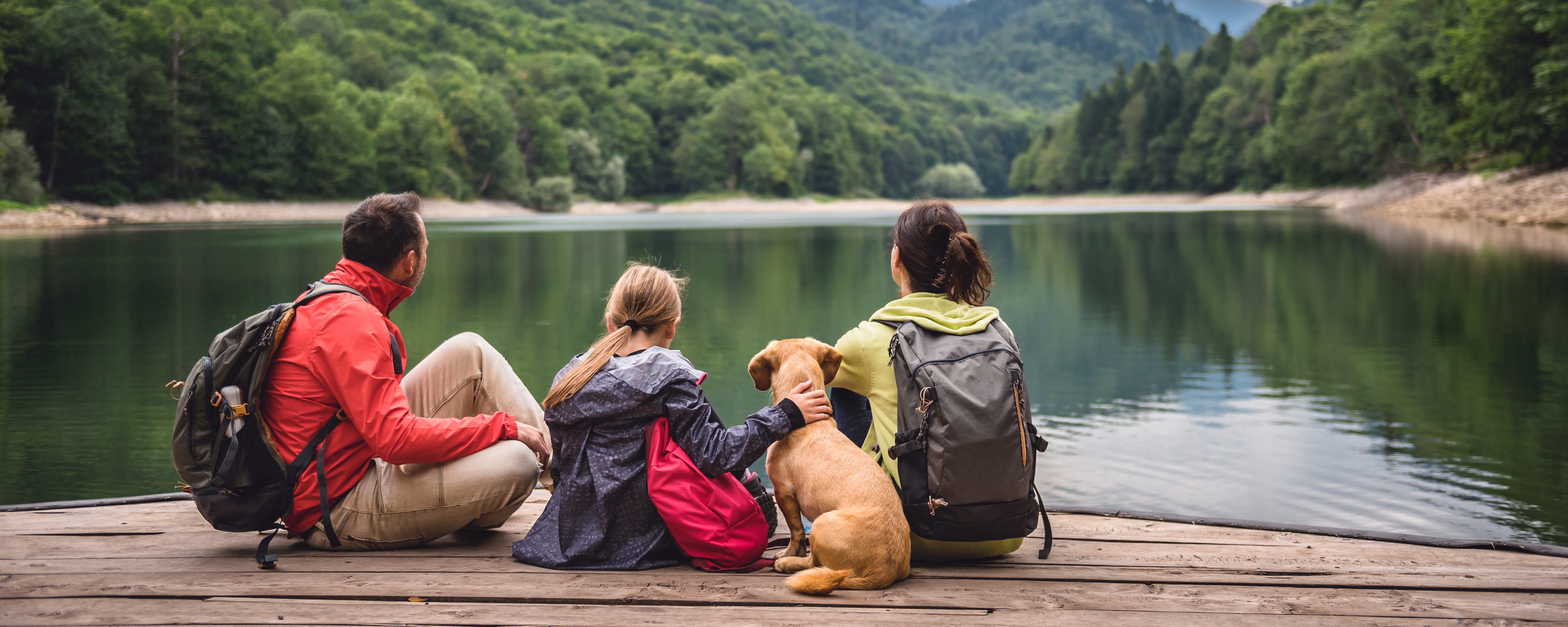 family and their dog hanging out on a dock over a lake