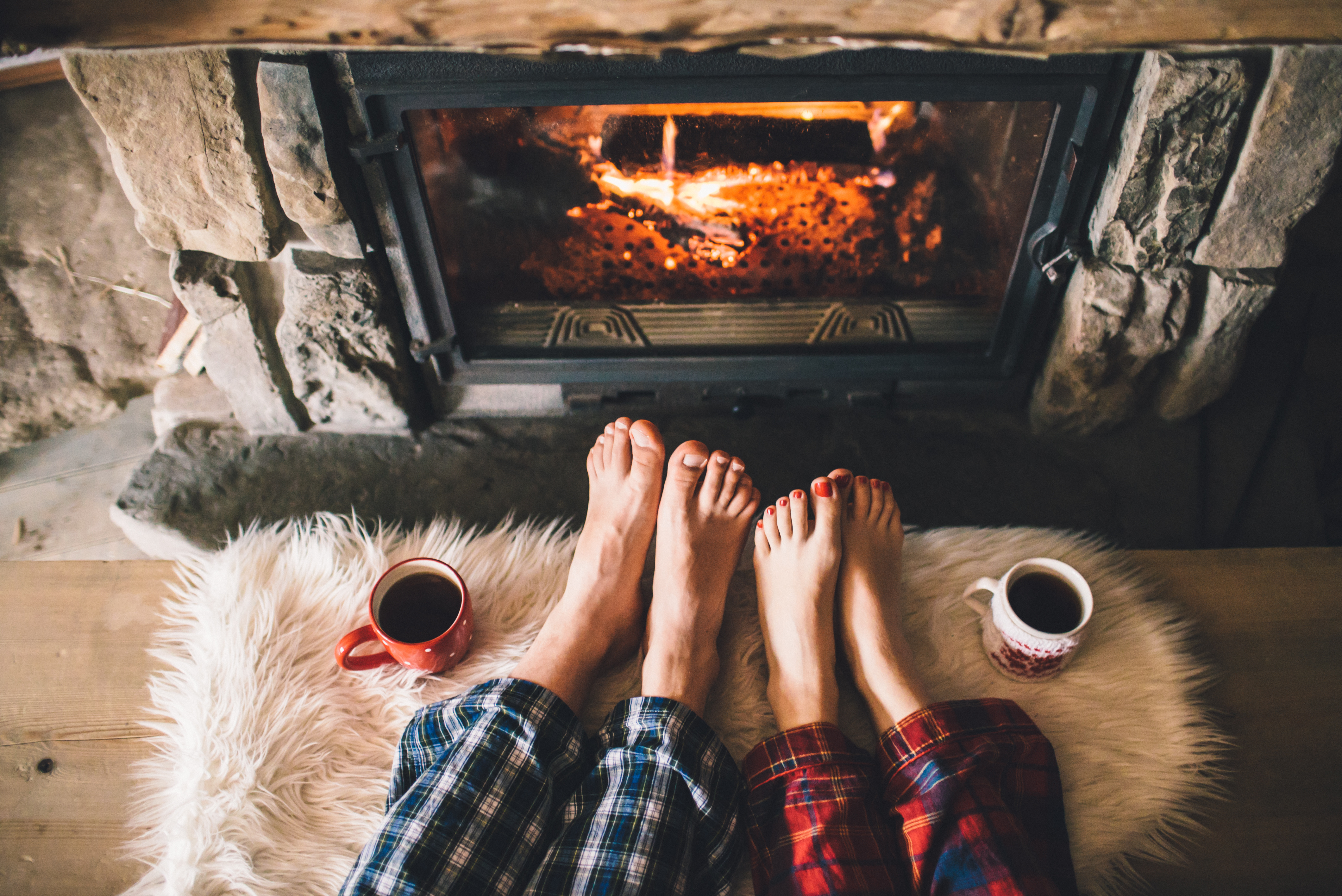Two people in pajamas warming their feet by the fire