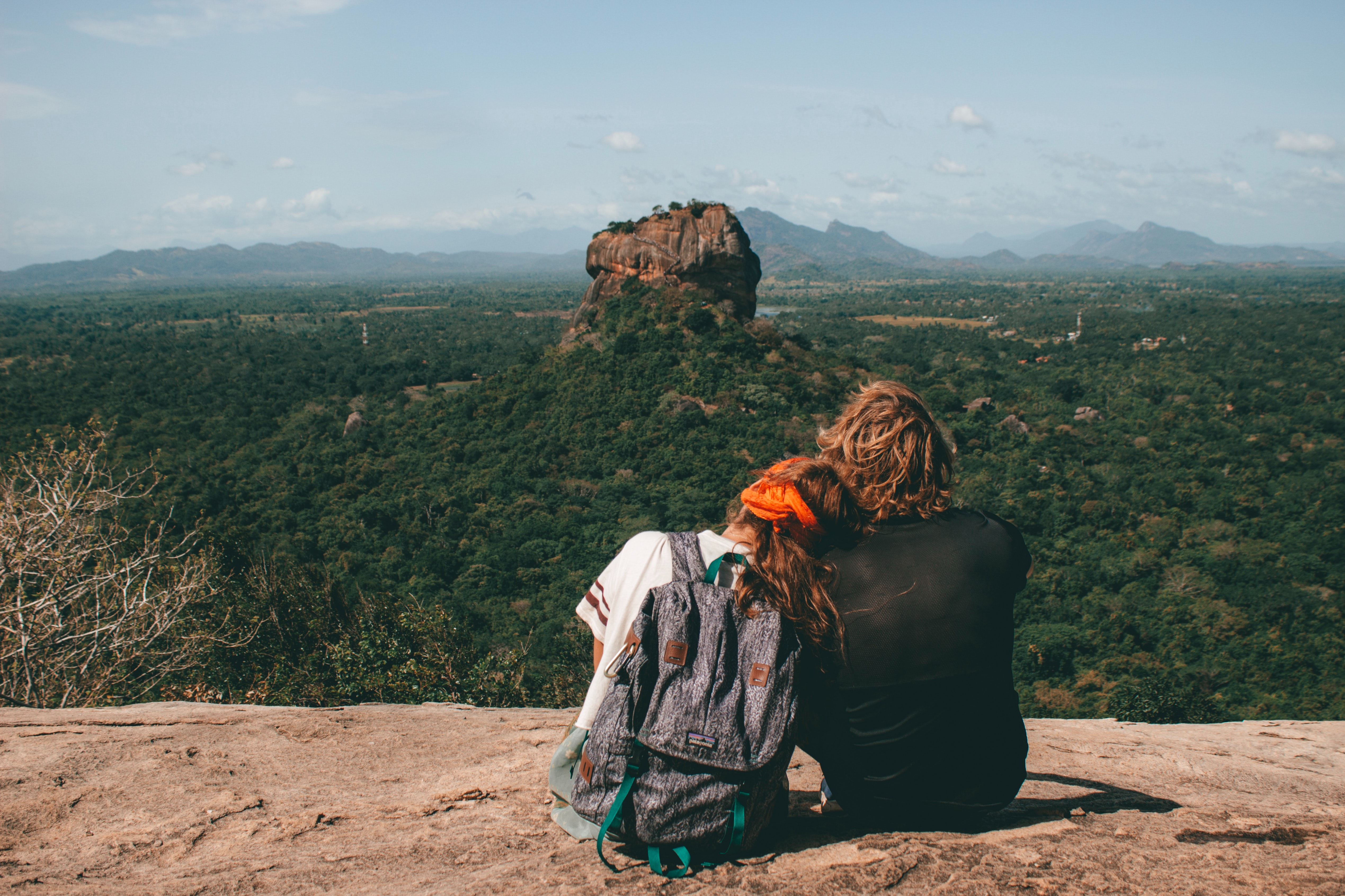 Couple hiking overlooking a canyon and a stacked rock.