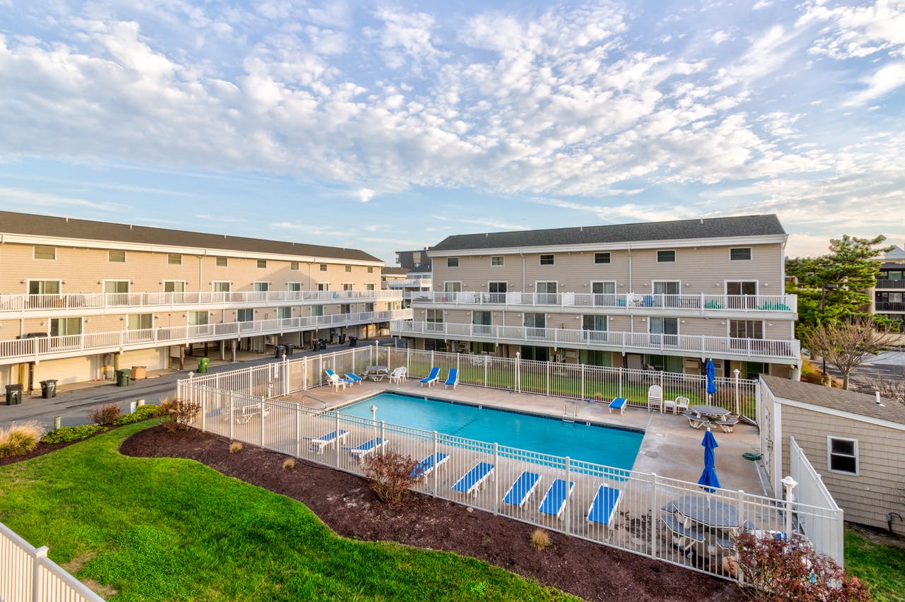 Multi-family style condo complex with a white fenced outdoor pool in Ocean City, MD