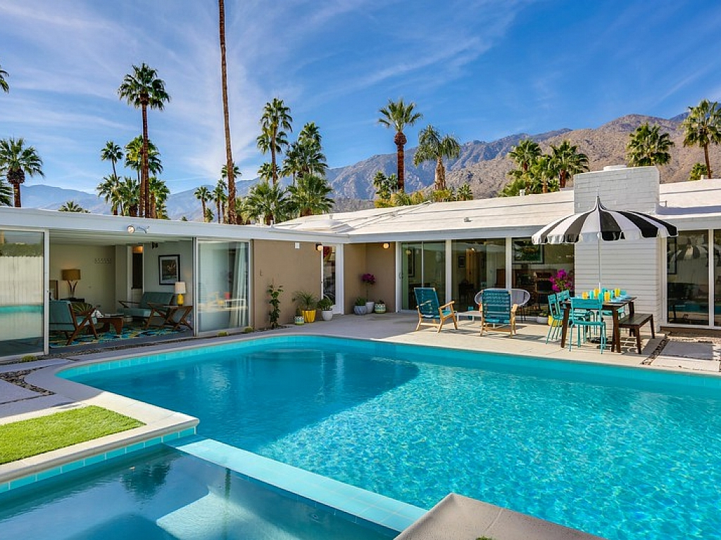 A vacation condo with an outdoor pool and furniture in Palm Springs, CA.