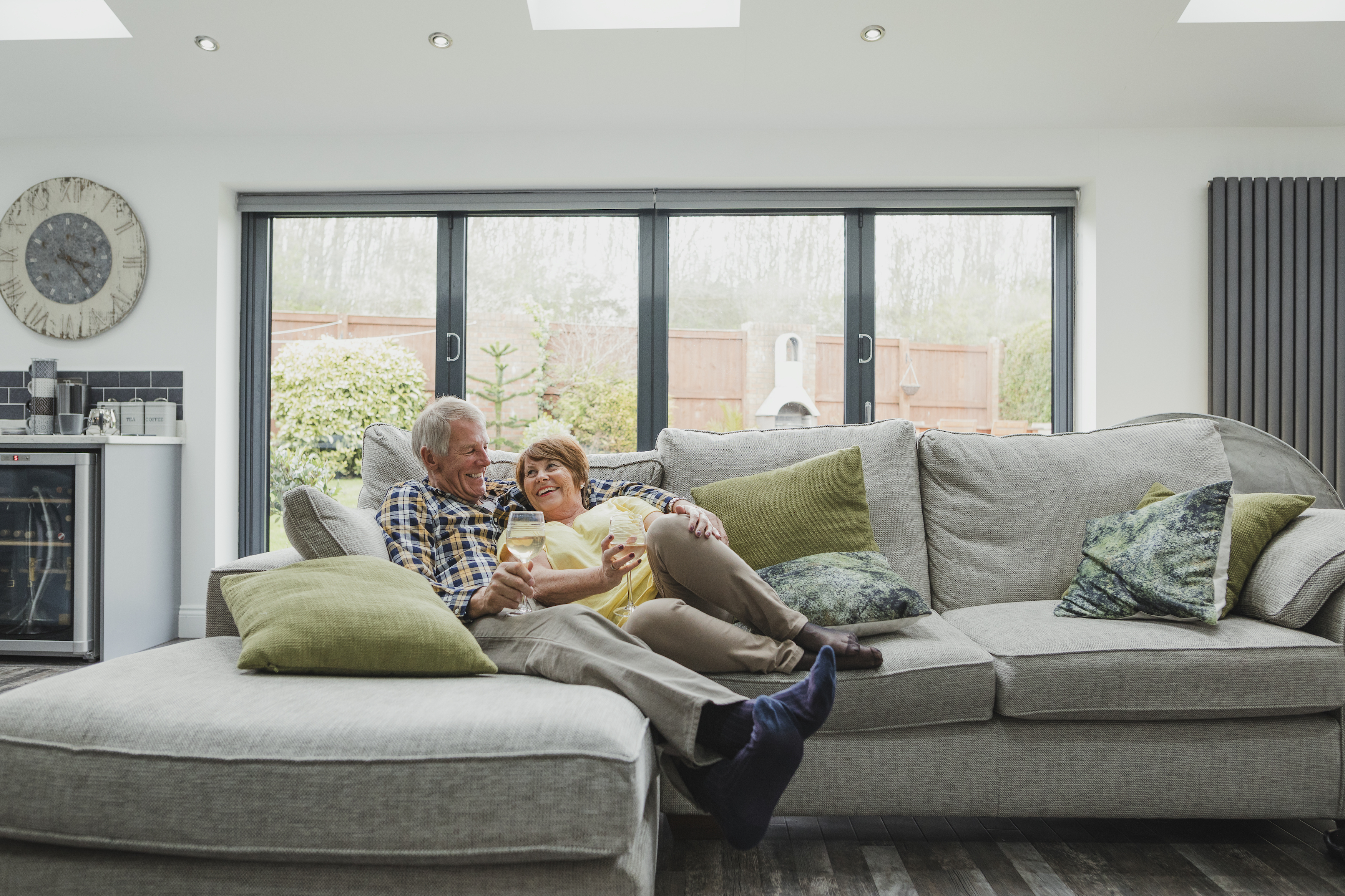 Elderly couple enjoying a glass of wine and relaxing on a couch in a living room