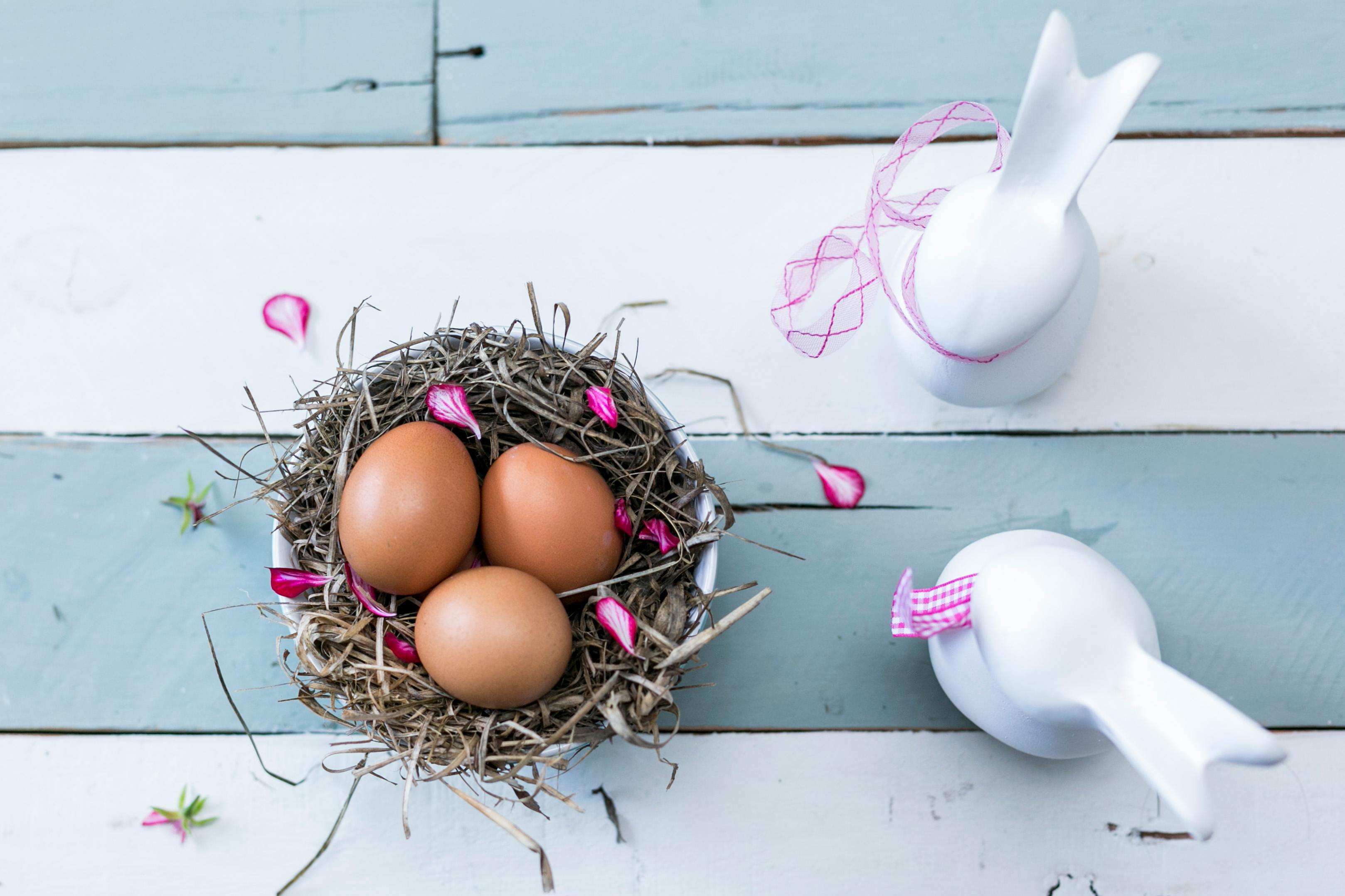 Eggs and two ceramic bunnies on a table.