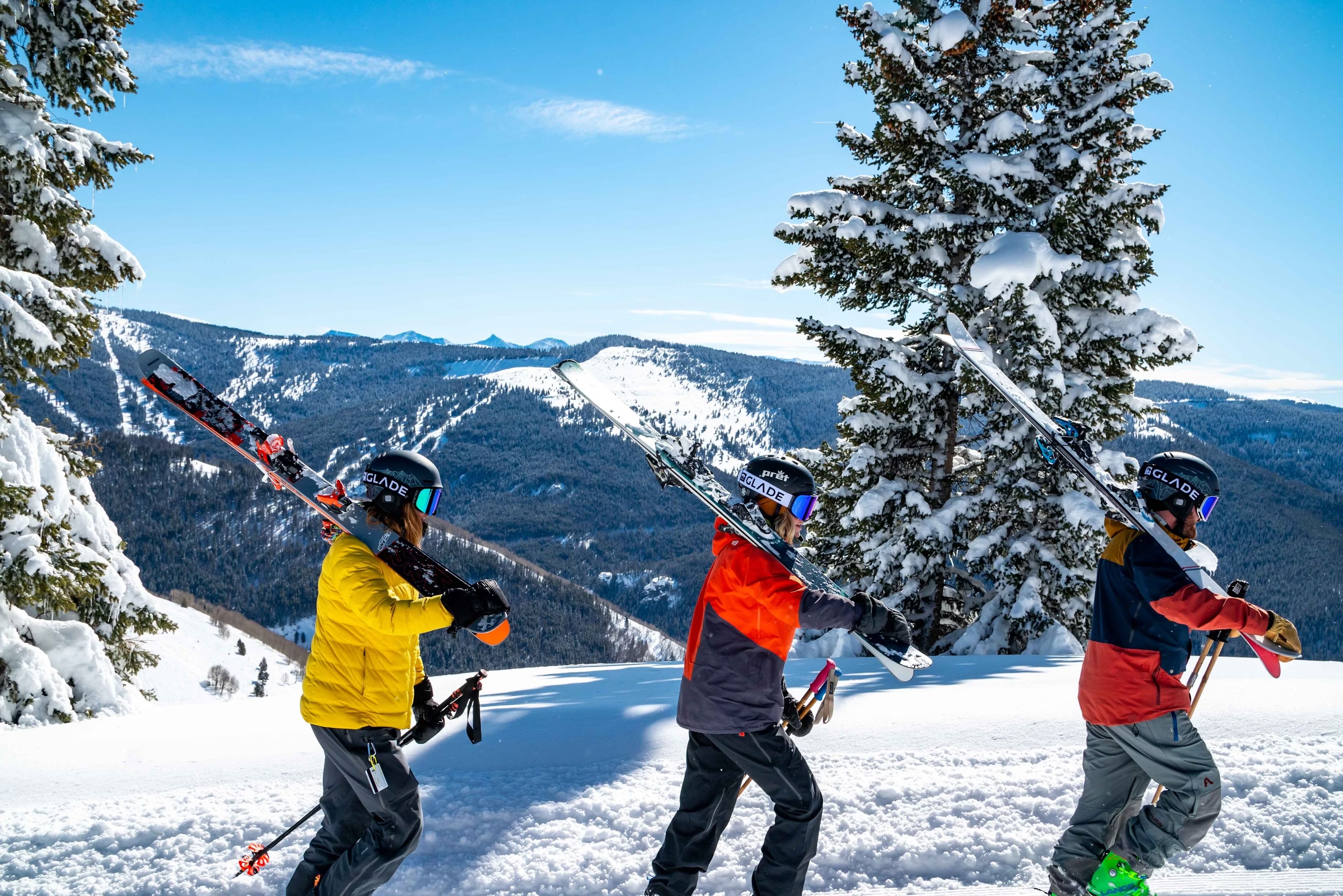 Skiers walking with skis on a mountain in snow.